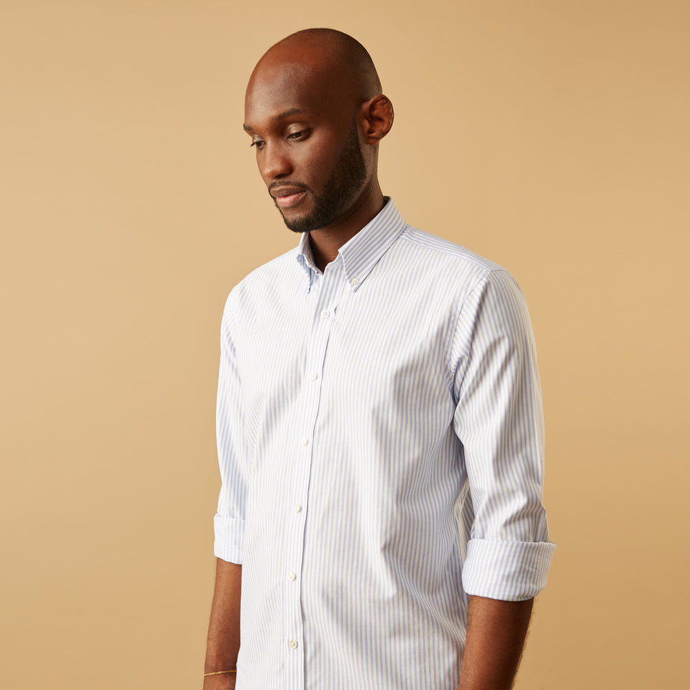 The Turnbull & Asser Pale Blue Stripe Weekend Fit Hayne Shirt features a Dorset collar, 1-button cuffs, and vertical stripes, shown laid flat against a white background.