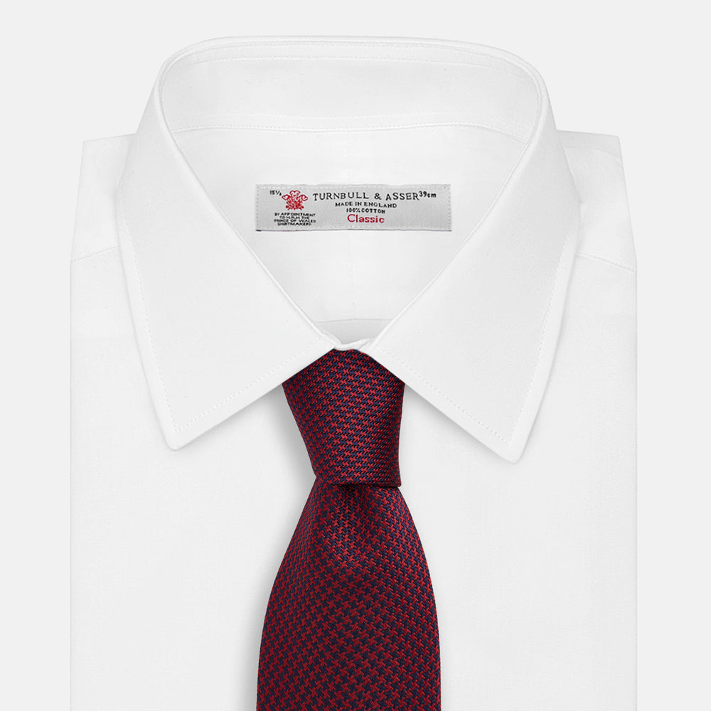 The HOUNDSTOOTH NAVY BURGUNDY TIE by Turnbull & Asser features a textured navy and burgundy silk woven pattern—an elegant staple for every gentleman’s wardrobe.