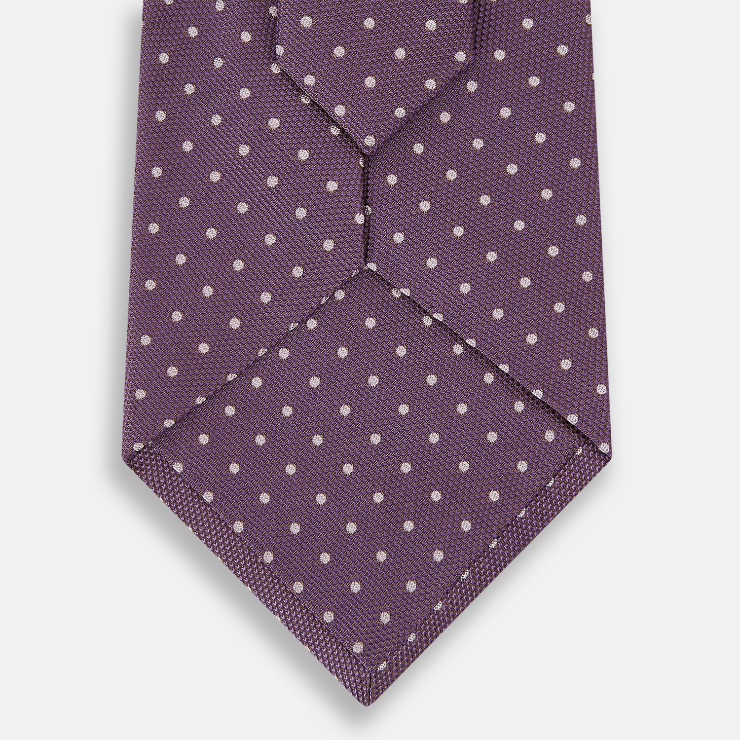View 3 of product The Turnbull & Asser Lilac and Purple Micro Dot Silk Tie, featuring small white dots, is a stylish accessory for smart attire. Displayed rolled-up on a light background.
