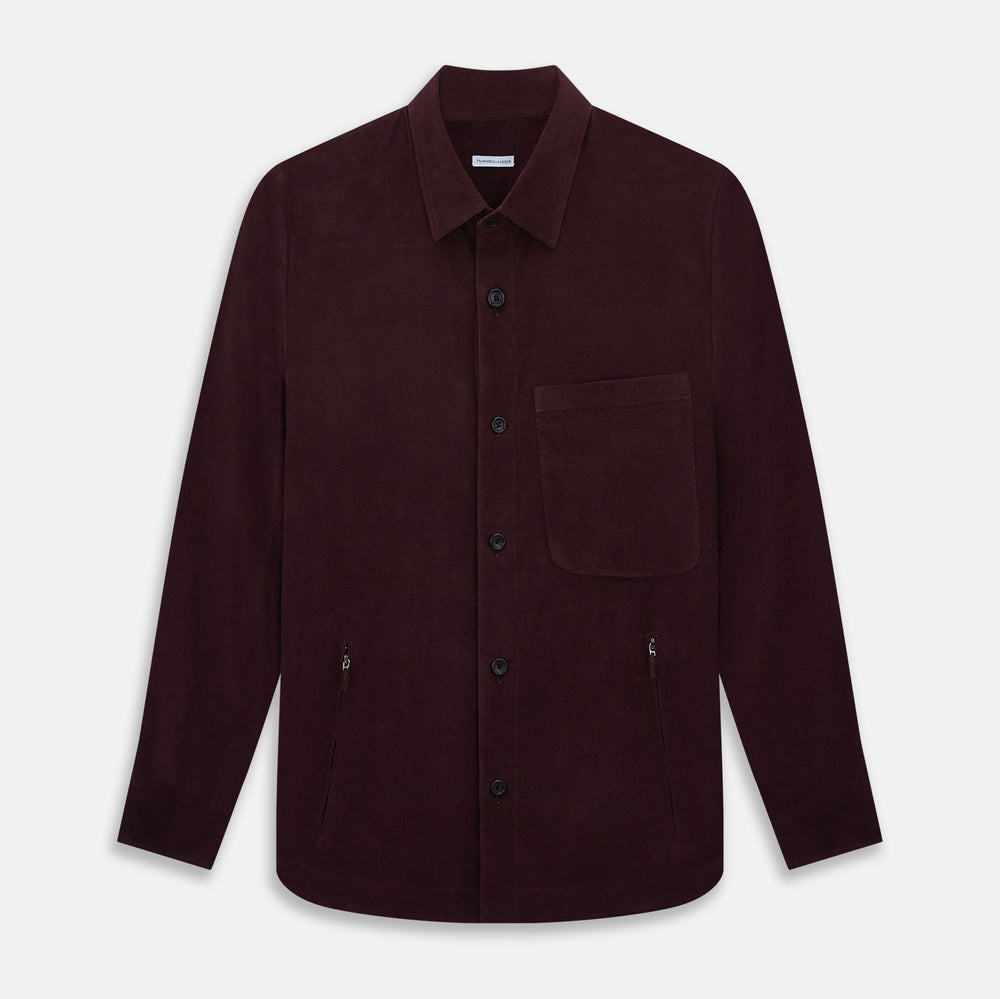 The Turnbull & Asser Burgundy Corduroy Hampstead Overshirt features long sleeves, a collar, a large left chest pocket, and two zippered side pockets, shown laid flat on a plain white background.