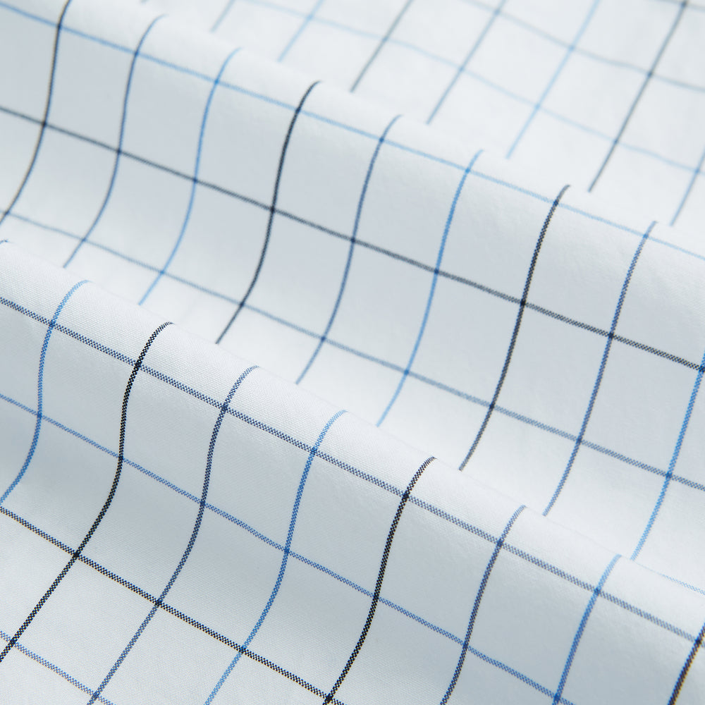 The Blue Grid Check Mayfair Shirt by Turnbull & Asser is a long-sleeve, button-up shirt with a T&A collar, crafted from organic cotton in a light and dark blue grid pattern, shown flat against a white background.