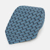 View 1 of product A close-up of the Turnbull & Asser Pale Blue and Navy Weave Patterned Silk Tie, featuring a textured geometric design. The silk tie is rolled at one end and displayed on a white background.