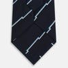 View 3 of product The Turnbull & Asser Navy Broken Shadow Stripe Silk Tie features British excellence with a light blue and white zigzag pattern and is shown rolled up on a plain white background.