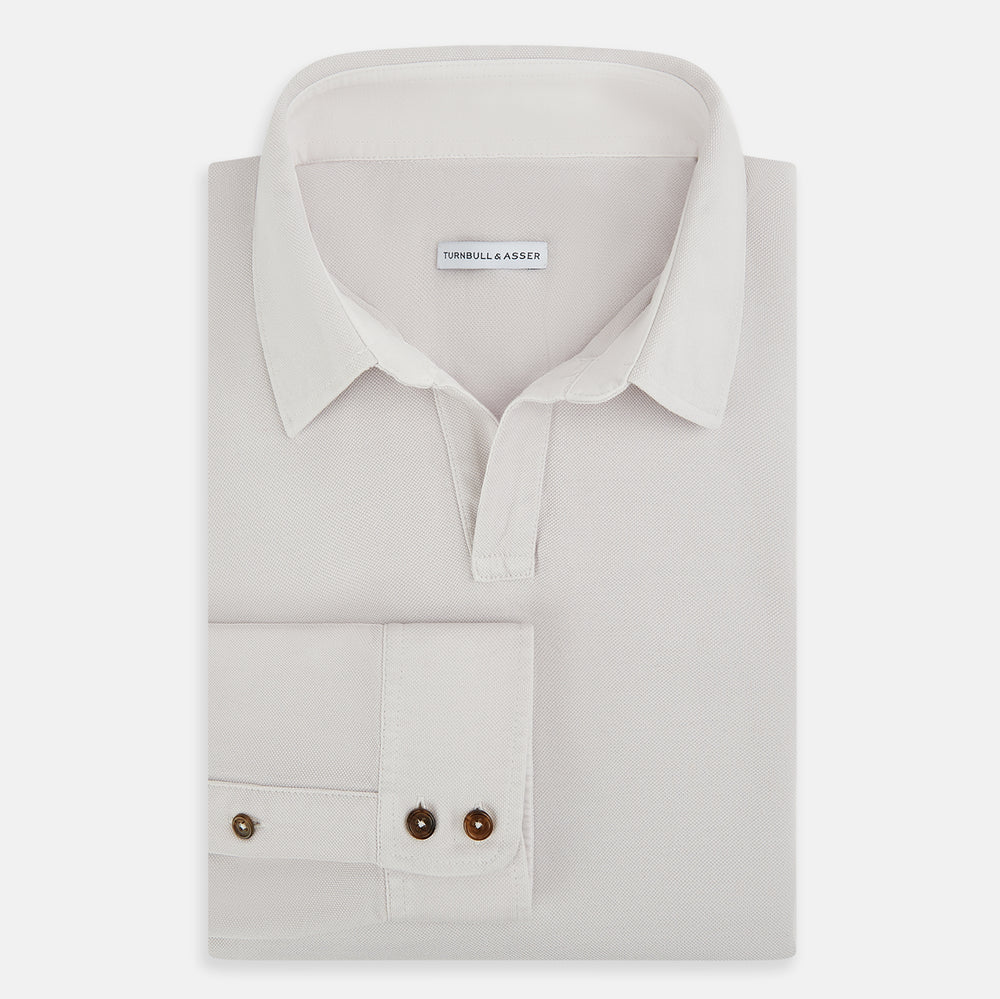 A pale pink luxury cotton rugby polo shirt by Turnbull & Asser, featuring long sleeves and a collar with no buttons, displayed flat on a white background.