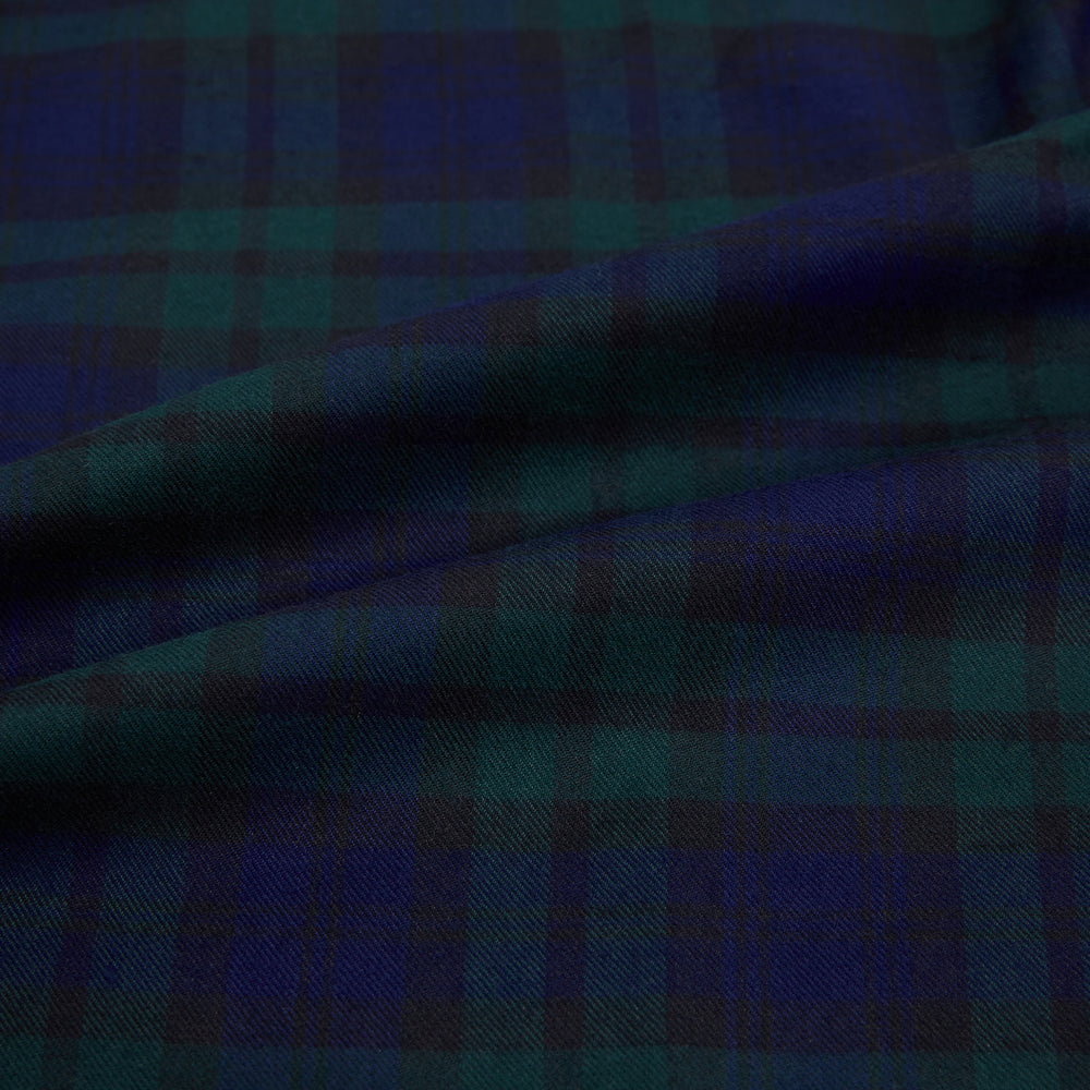 The Turnbull & Asser Black Watch Tartan Windsor Shirt is a long-sleeve, button-up shirt with a dark green and navy tartan pattern, white buttons, collar, and curved hem—showcasing British craftsmanship on a plain white background.