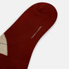 View 3 of product The Turnbull & Asser Burgundy Wool Check Mid-Length Sock features a dark red base with beige, white, and light brown argyle diamonds on the calf, shown against a plain white background.