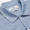 View 3 of product The Turnbull & Asser Slate Blue Chambray Holiday Fit Fellows Shirt features long sleeves and a classic collar, laid flat on a white background—a versatile summer piece for any occasion.