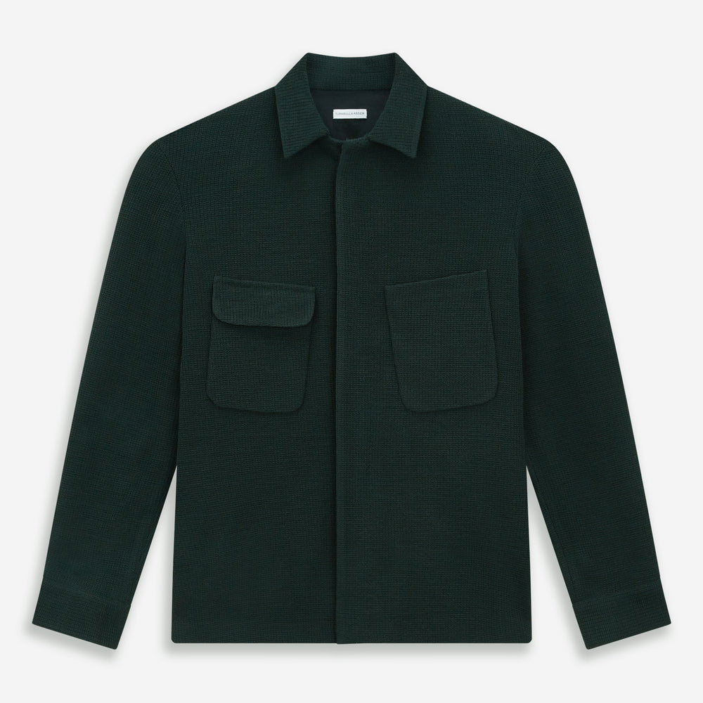 The Forest Green Greenwich Knitted Overshirt by Turnbull & Asser, crafted from Italian wool, features long sleeves, a collar, front buttons, and two chest pockets—one flap, one open—shown on a white background.