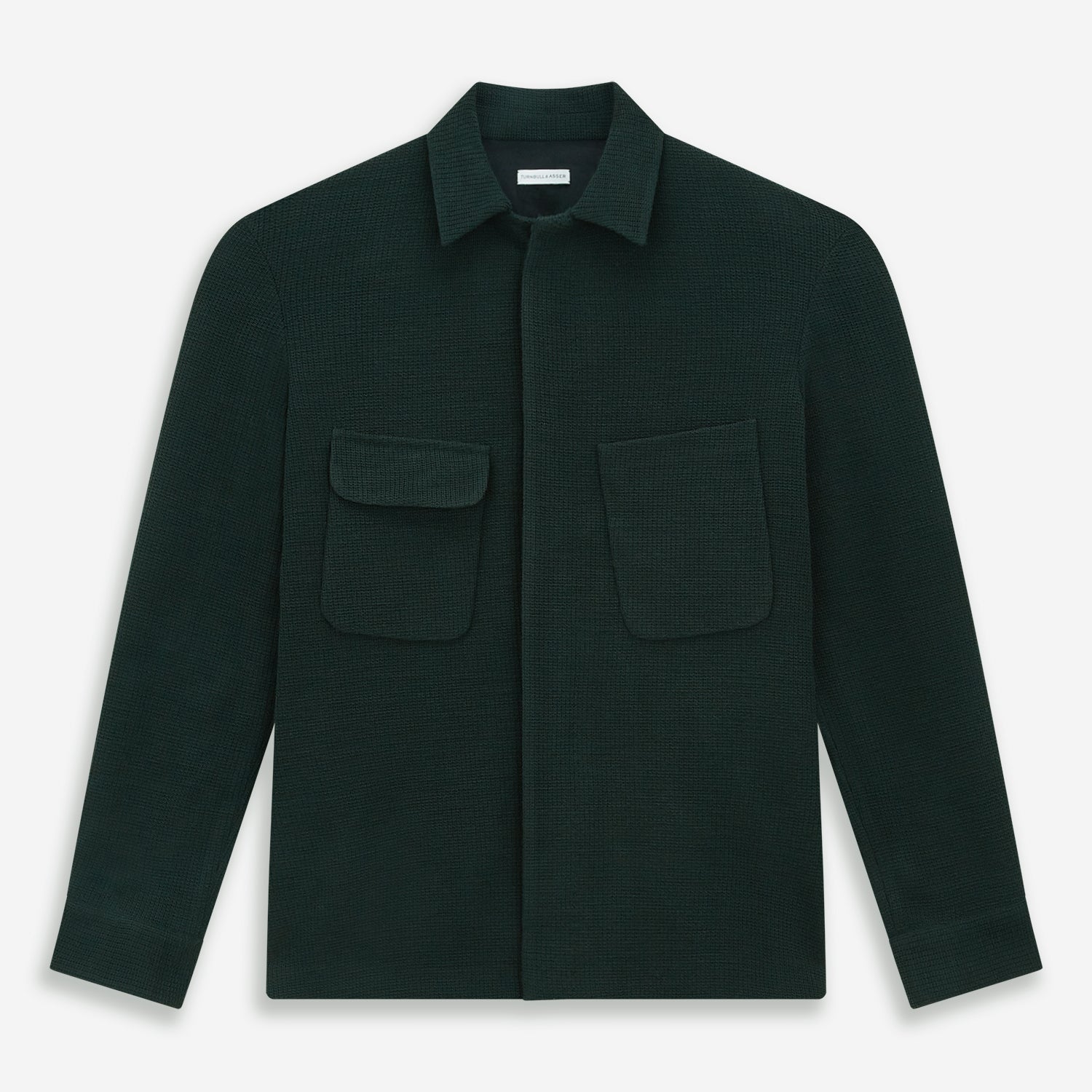 View 1 of product The Forest Green Greenwich Knitted Overshirt by Turnbull & Asser, crafted from Italian wool, features long sleeves, a collar, front buttons, and two chest pockets—one flap, one open—shown on a white background.