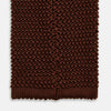 View 4 of product The Turnbull & Asser KNITTED BROWN SILK PLAIN TIE—a stylish, textured accessory—appears rolled up on a white background, perfect for elevating smart outfits.