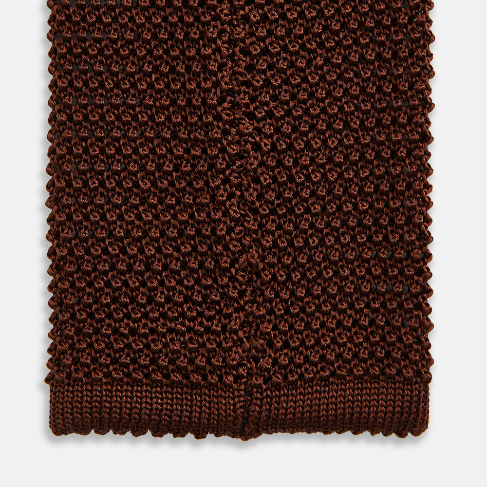 The Turnbull & Asser KNITTED BROWN SILK PLAIN TIE—a stylish, textured accessory—appears rolled up on a white background, perfect for elevating smart outfits.
