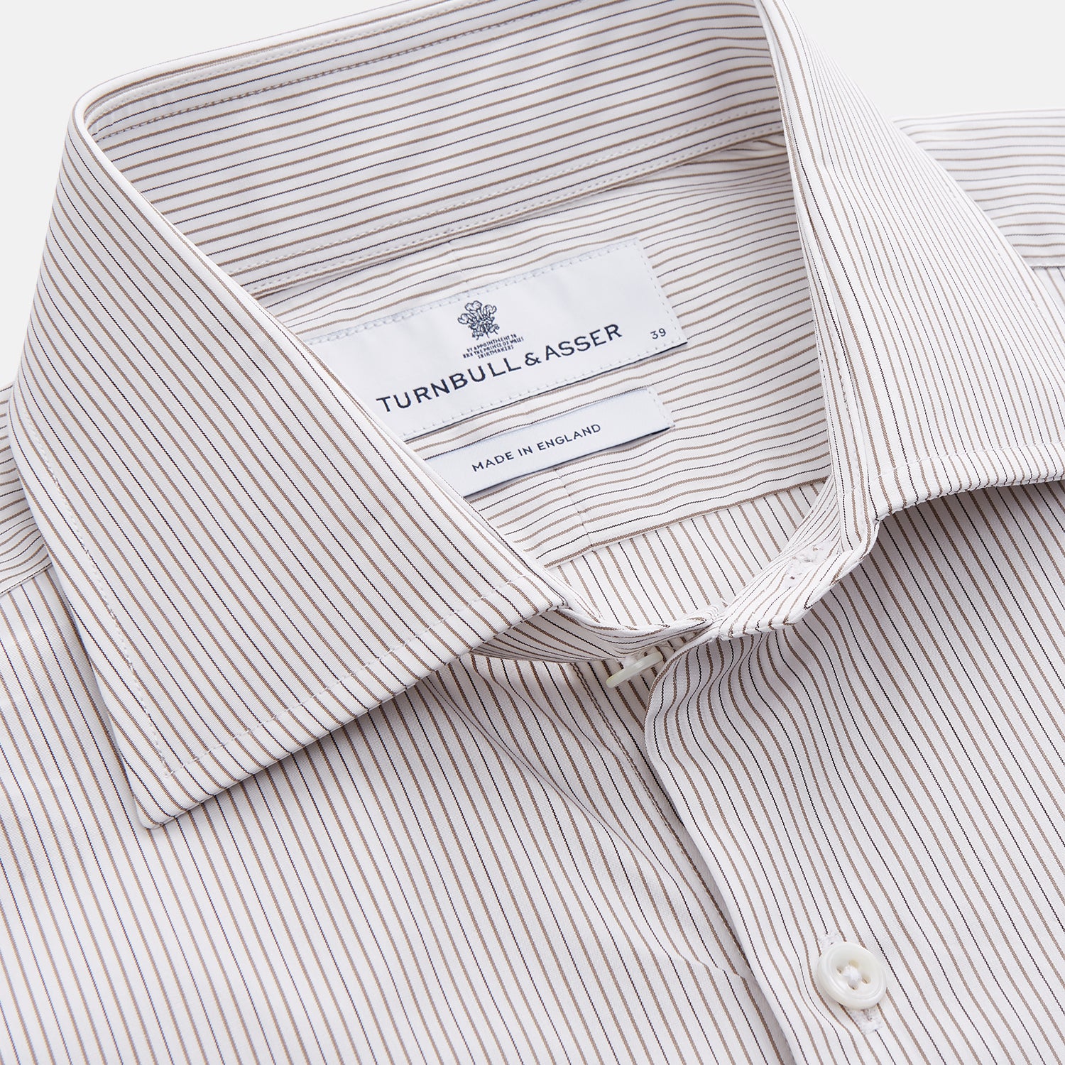 View 2 of product The Turnbull & Asser Sandstone Multi Stripe Cotton Tailored Fit Shelton Shirt features subtle vertical stripes, a pointed collar, and long sleeves, shown flat on a plain white background.