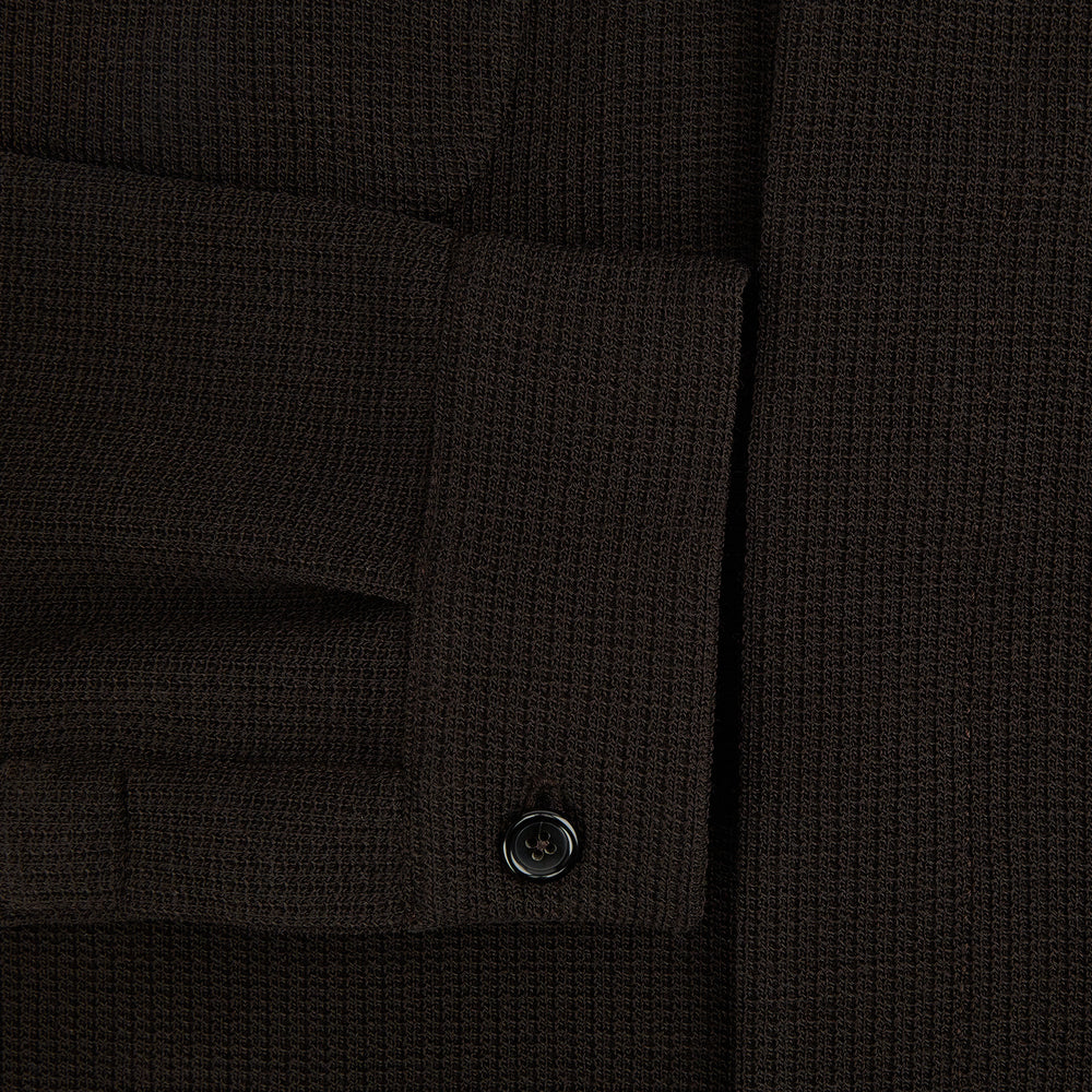 The Turnbull & Asser Dark Chocolate Greenwich Knitted Overshirt is crafted from Italian wool, with a classic collar, two flap chest pockets, and a concealed button front—offering a sleek cardigan alternative. Shown on a white background.