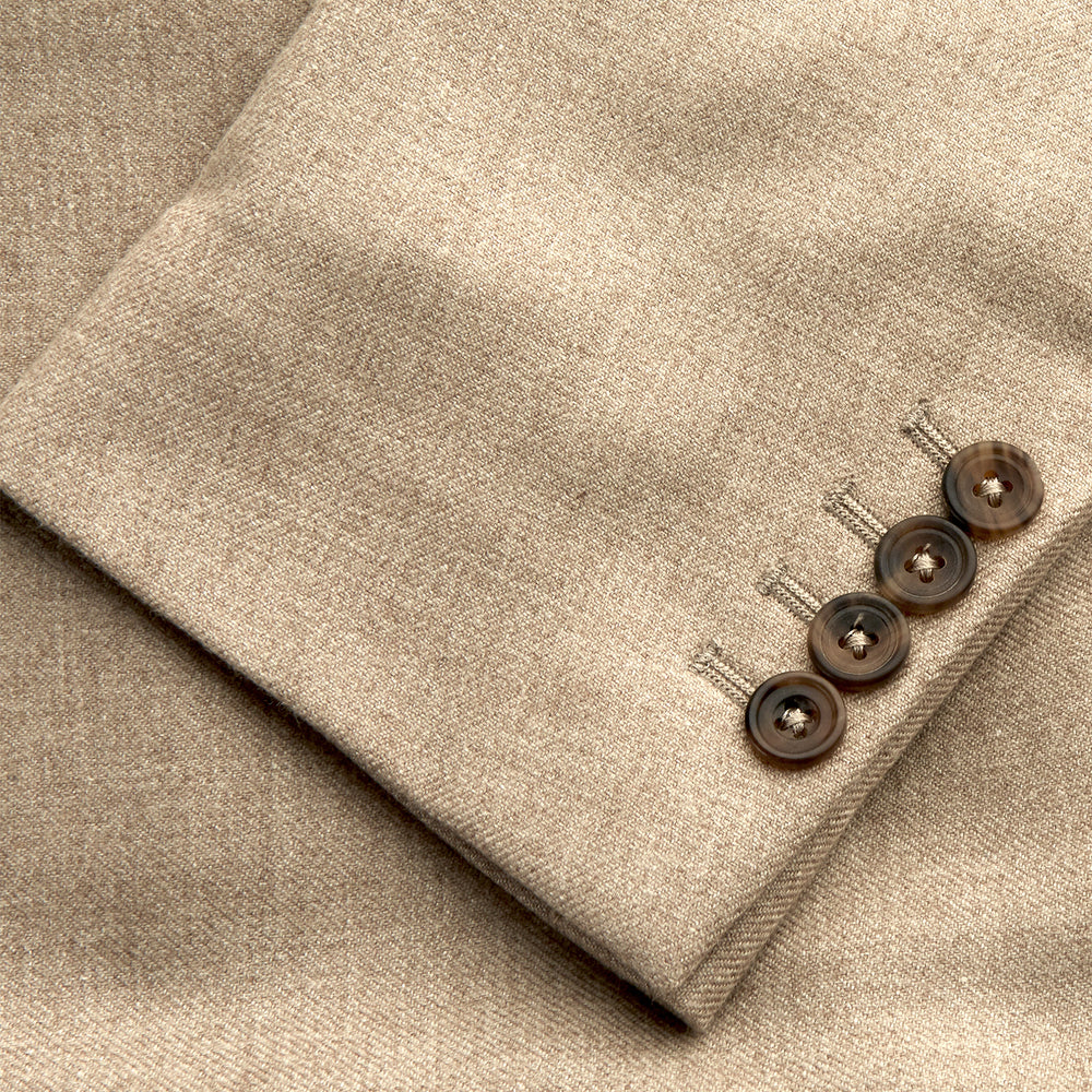 A man wearing the Beige Wool, Silk and Cashmere Bern Jacket by Turnbull & Asser over a matching shirt and olive green pants stands against a plain light gray background, looking to his left with a neutral expression.