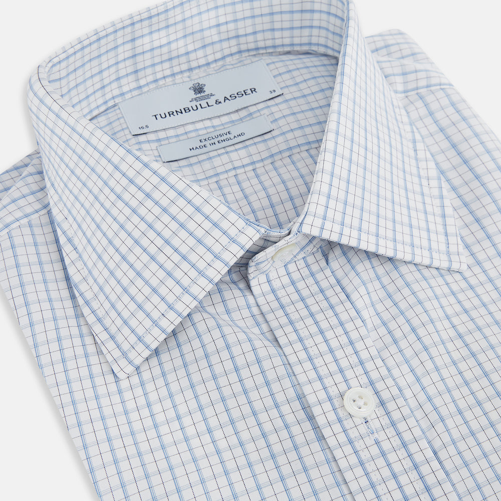 The Turnbull & Asser Sky Blue Combination Graph Check Mayfair Shirt features long sleeves, a pointed collar, buttoned cuffs, and a blue and white check pattern that showcases British craftsmanship. Displayed on a white background.