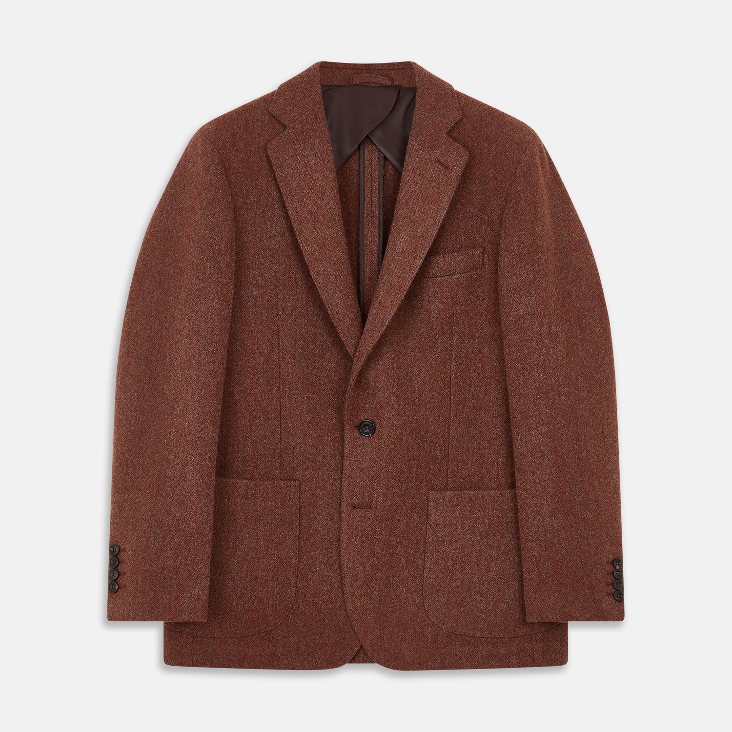 View 2 of product A man stands in a lush garden, hands in pockets and relaxed, wearing the Turnbull & Asser Red Lambswool Herringbone Bern Blazer, a striped dress shirt, patterned scarf, and dark trousers.