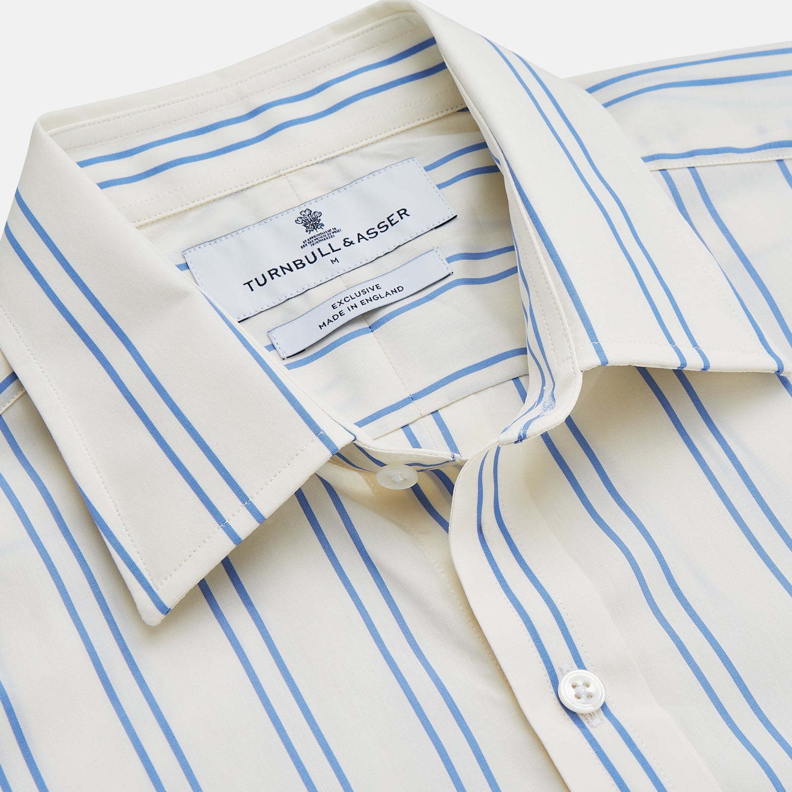 View 3 of product A man with short brown hair stands against a beige background in a Turnbull & Asser Blue and Off-White Stripe Cotton Weekend Fit Finch Shirt, featuring vertical stripes and a Derby collar, paired with dark pants. One hand is in his pocket; he has a neutral expression.