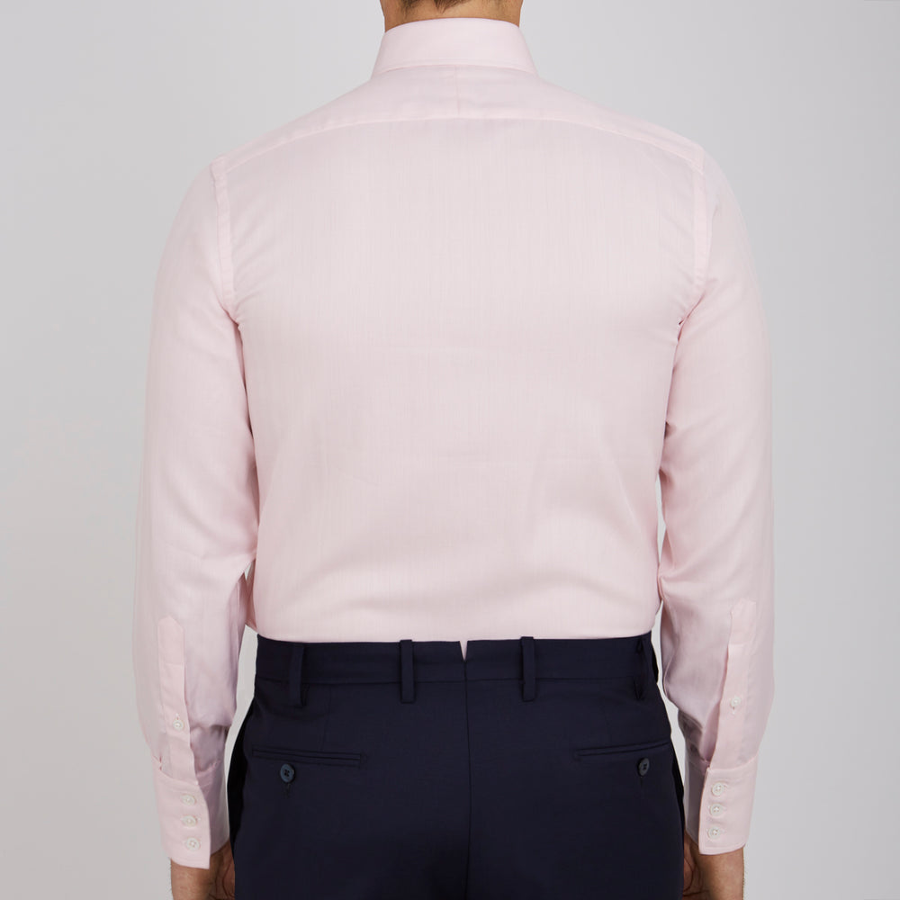 A Pink Herringbone Superfine Cotton Shirt by Turnbull & Asser, featuring a T&A collar and 3-button cuffs, is neatly folded with the inner collar label visible and white buttons, set against a plain white background.