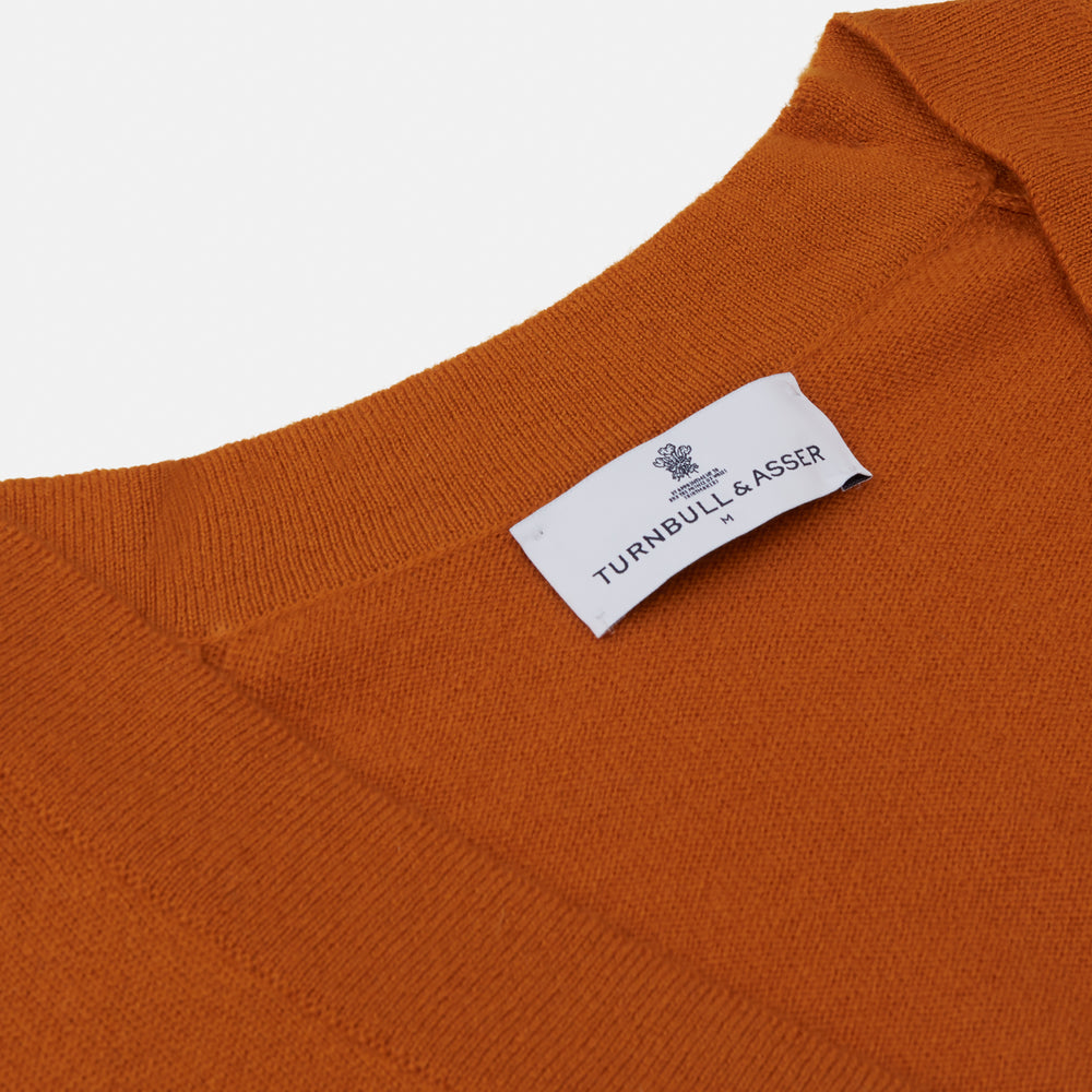 The Rust Lachlan Cashmere Cardigan by Turnbull & Asser features a V-neck, long sleeves, front button closure, and two front pockets—ideal for layering in smart-casual looks. Shown laid flat on a plain white background.