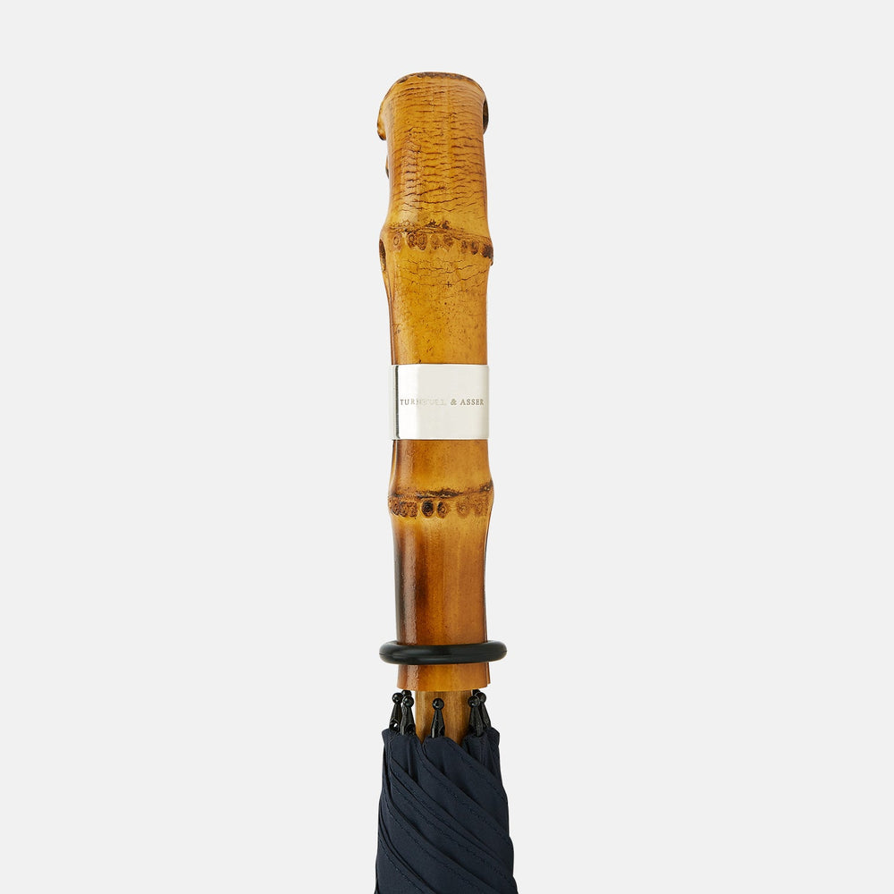 The Turnbull & Asser Navy Umbrella with Whangee Crook Handle is fully open, displaying its dark blue canopy and wooden curved handle against a plain white background.