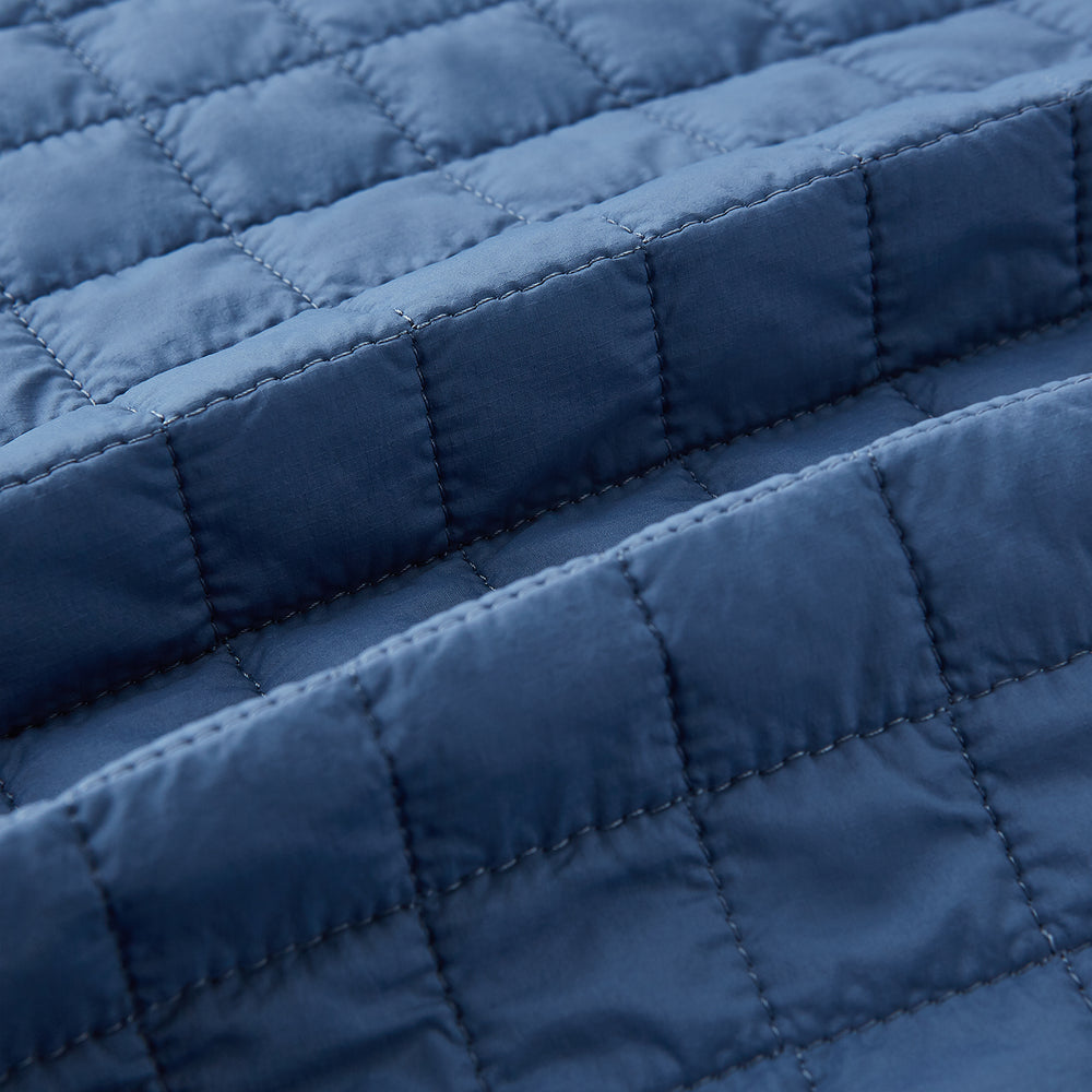 The Azzurro Double-Breasted Quilted Gilet by Turnbull & Asser is a sleeveless blue piece with black buttons, two zippered pockets, and a chest pocket—ideal for layered looks against a plain white background.