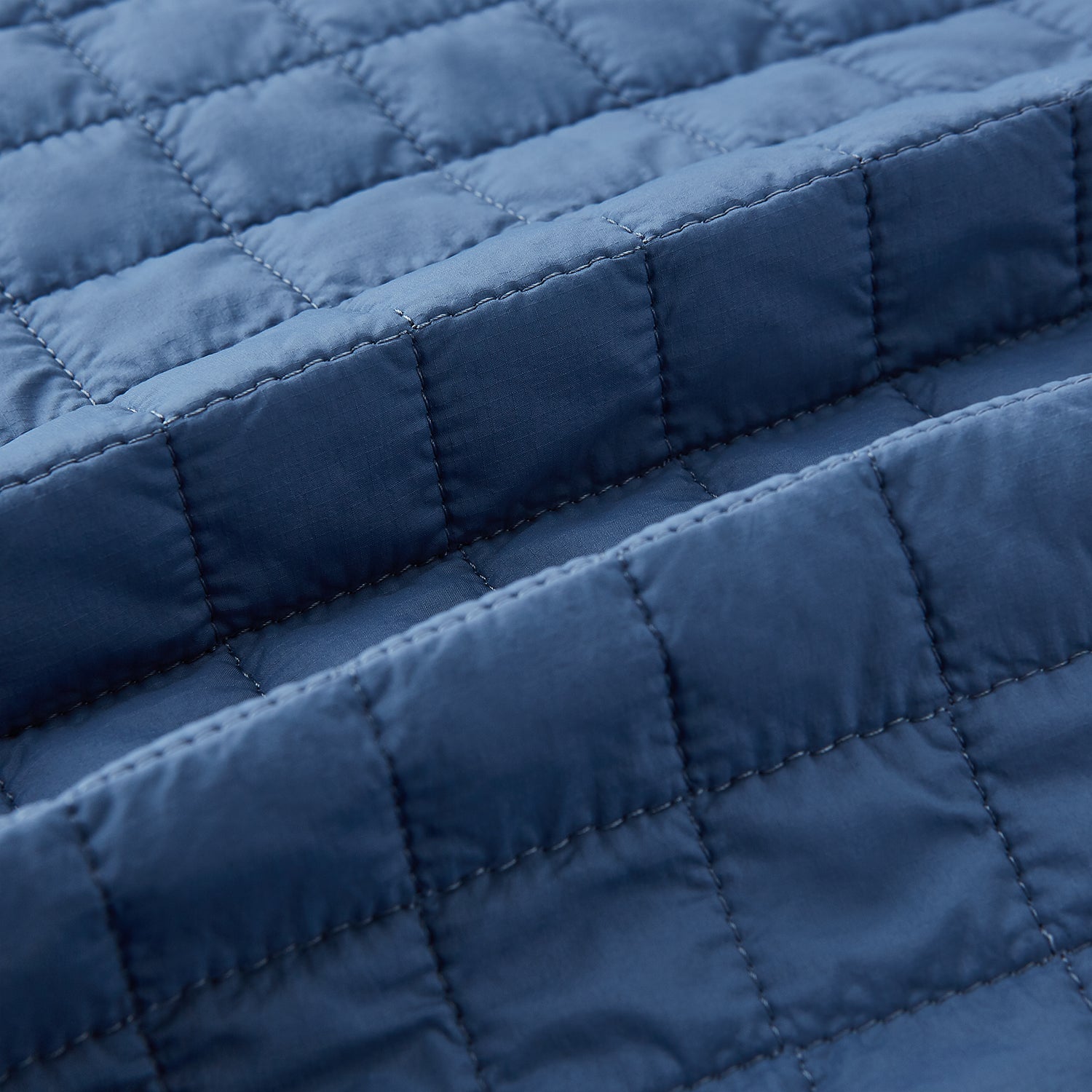 View 4 of product The Azzurro Double-Breasted Quilted Gilet by Turnbull & Asser is a sleeveless blue piece with black buttons, two zippered pockets, and a chest pocket—ideal for layered looks against a plain white background.