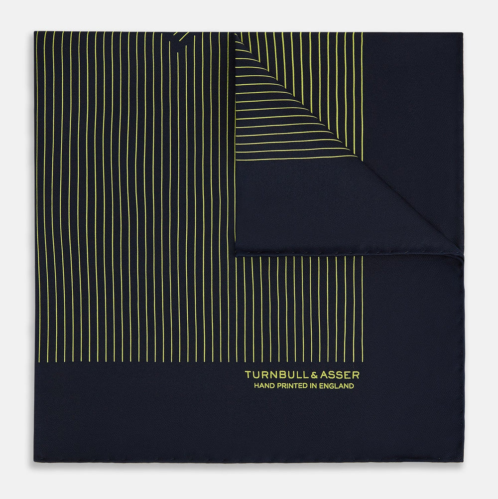 The Turnbull & Asser Navy and Gold Stripe Silk Pocket Square features light yellow vertical stripes, a folded corner, and "TURNBULL & ASSER HAND PRINTED IN ENGLAND" in gold at the bottom right.