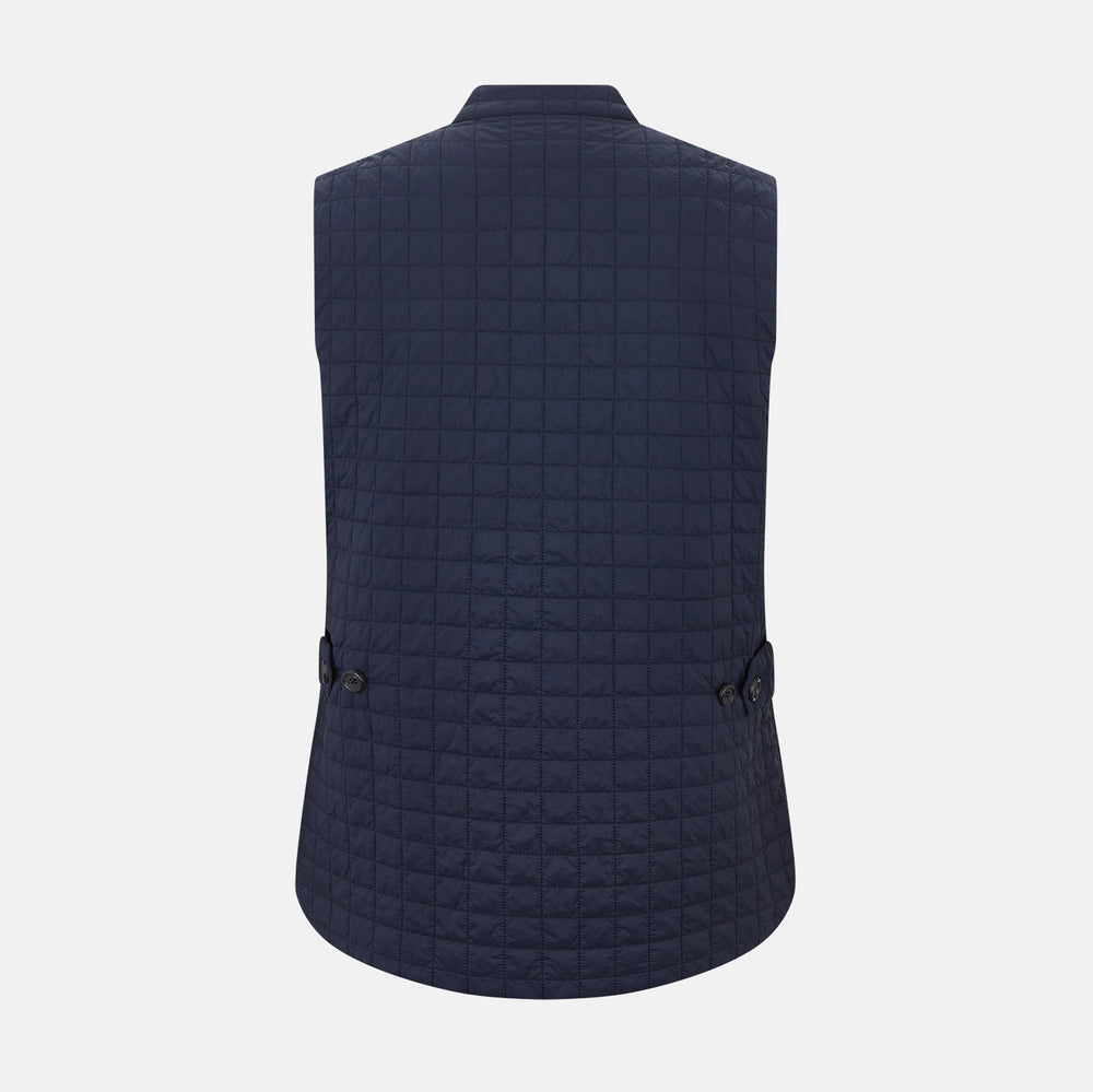 The Turnbull & Asser Navy Double-Breasted Quilted Gilet is a sleeveless piece with an asymmetrical button closure, chest pocket, and two zippered side pockets, shown on a plain white background—ideal for layered dressing.