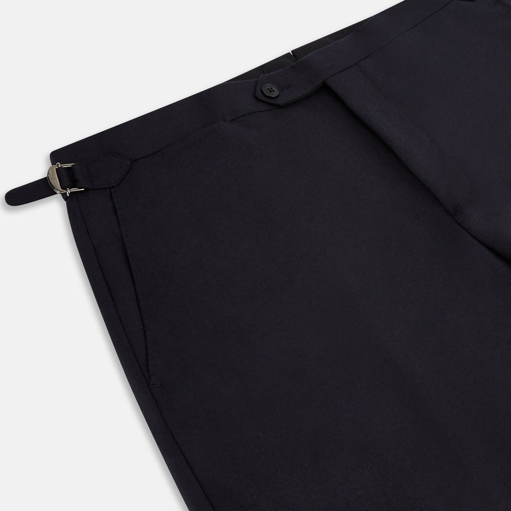 The Turnbull & Asser Short Navy Single Breasted Suit is shown flat on a white background, with a notch lapel jacket featuring two front pockets and matching trousers neatly folded underneath.