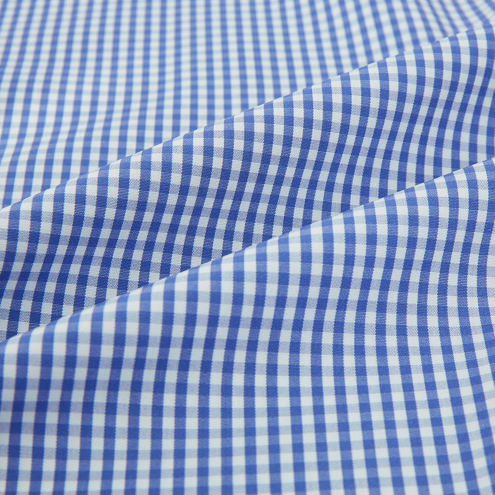 The Turnbull & Asser Blue Grid Check Belgravia Shirt, made from pure cotton with long sleeves, a spread collar, buttoned cuffs, and a blue-and-white check pattern, is laid flat on a white background.
