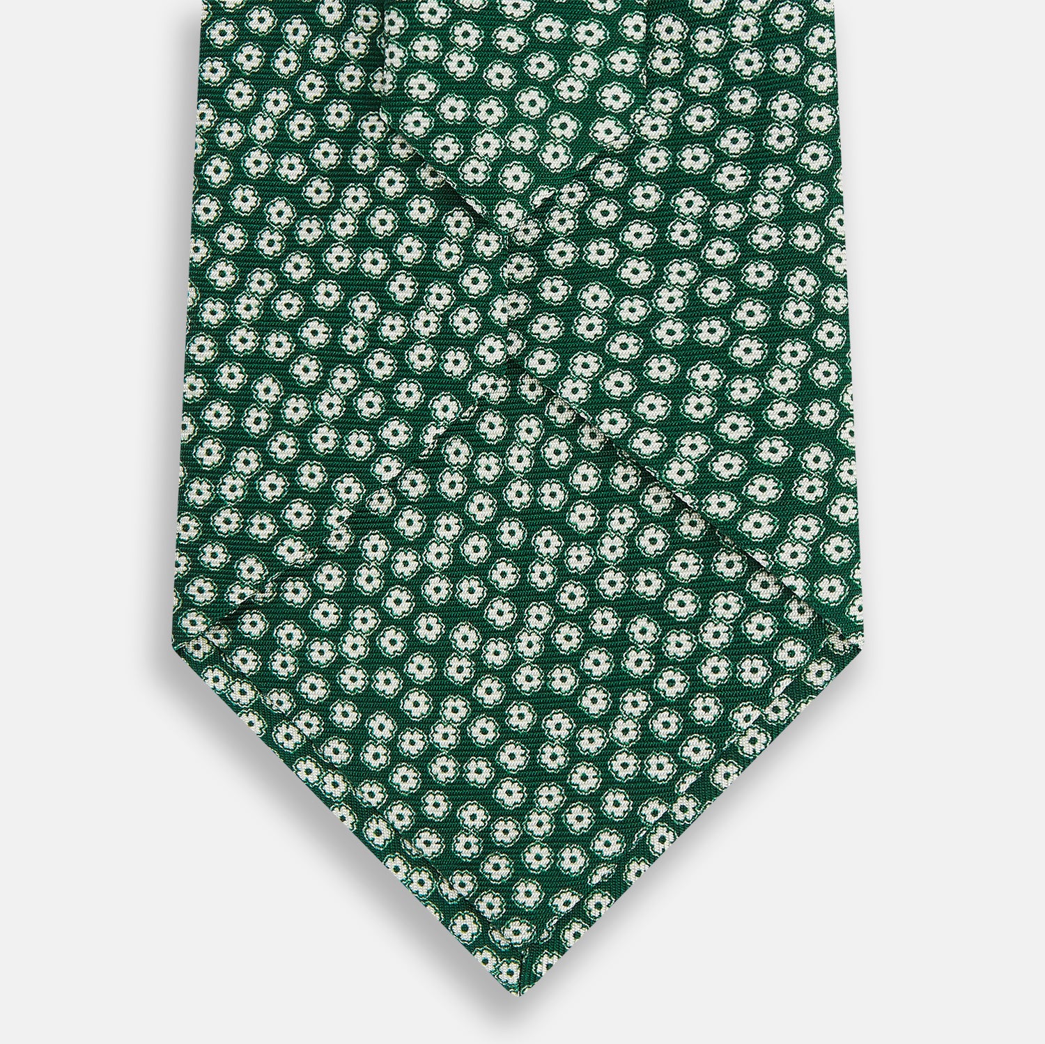 View 3 of product The Forest Green Flower Patterned Silk Tie by Turnbull & Asser features a white floral motif on silk, shown neatly rolled against a plain white background.