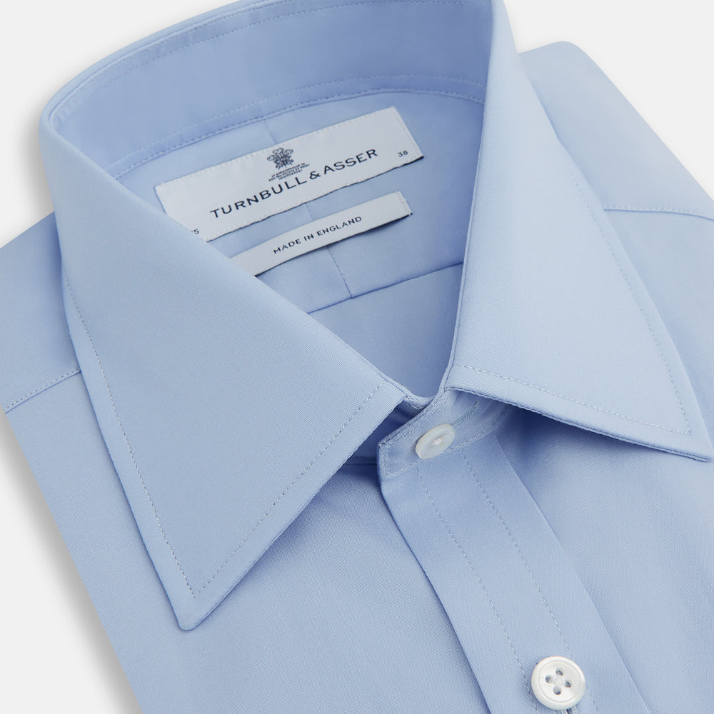 The Turnbull & Asser Blue Cotton Shirt features a T&A collar, 3-button cuffs, and white buttons—ideal for navy suits or smart looks. Laid flat on a white background.
