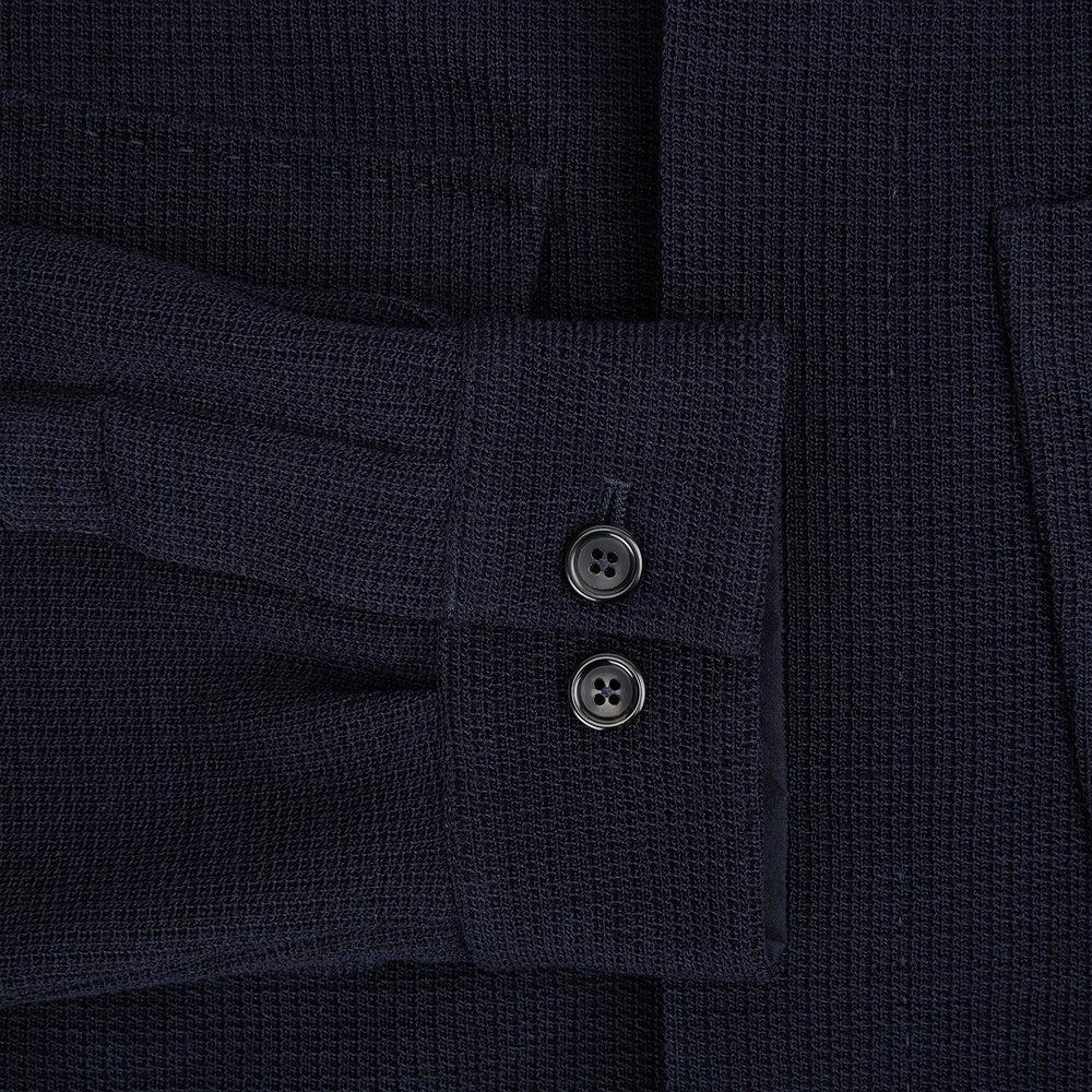 The Turnbull & Asser Navy Greenwich Knitted Overshirt, made from Italian wool with a collar, two front flap pockets, and a hidden button placket, is shown laid flat on a white background.