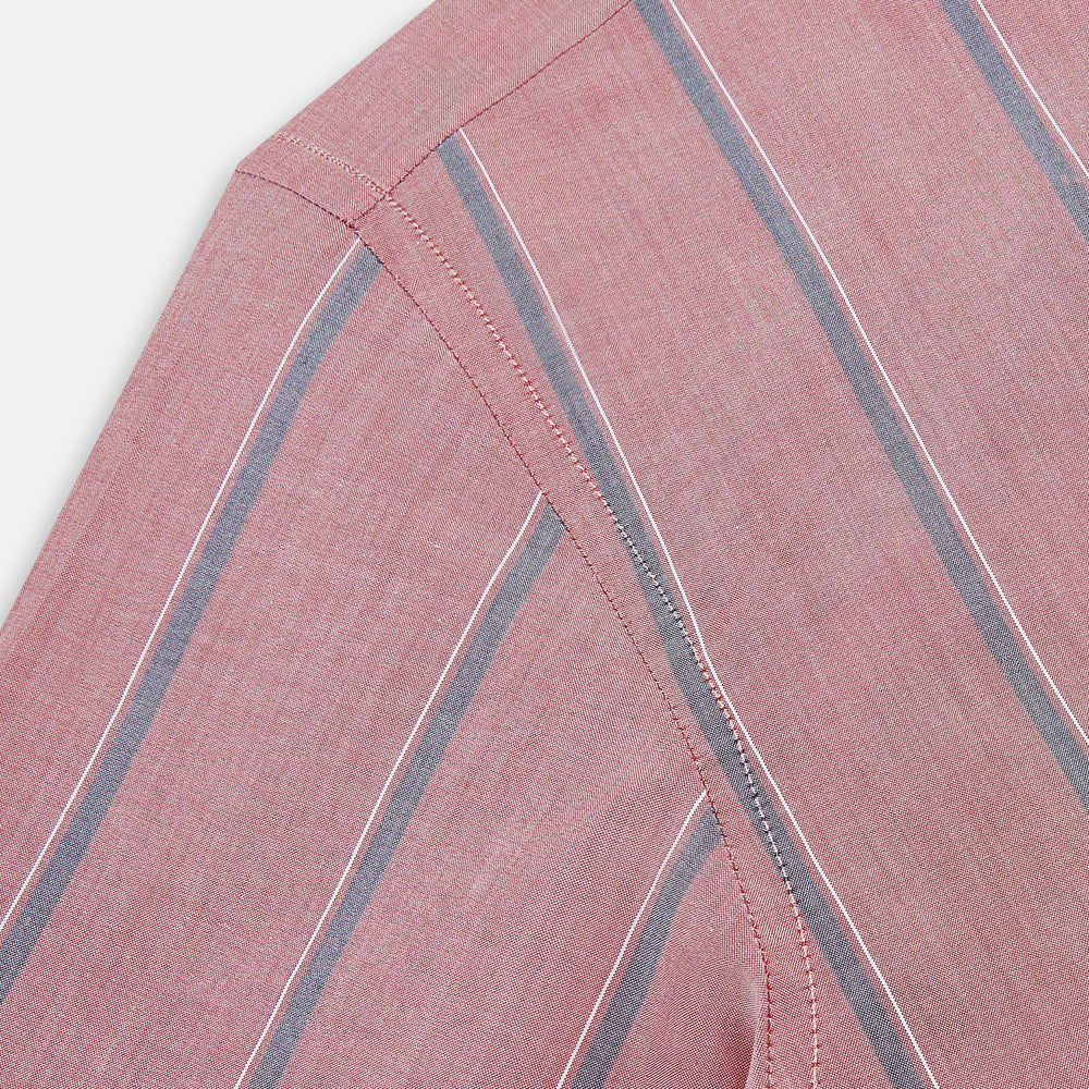 The Turnbull & Asser Red Track Stripe Westminster Shirt features British craftsmanship, a collar, pink base with vertical blue and white stripes, white buttons, and a pocket-free front for refined appeal.