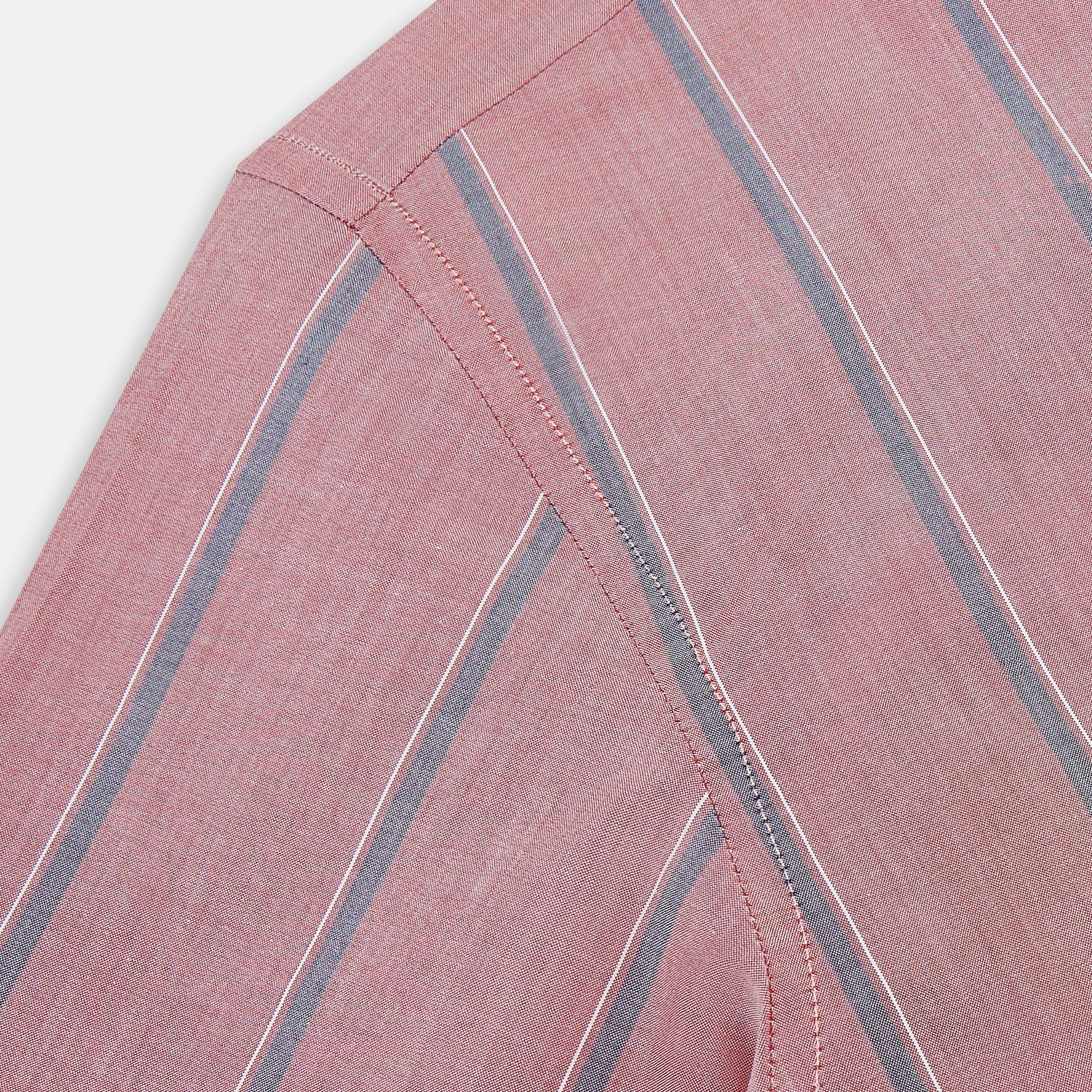 View 6 of product The Turnbull & Asser Red Track Stripe Westminster Shirt features British craftsmanship, a collar, pink base with vertical blue and white stripes, white buttons, and a pocket-free front for refined appeal.