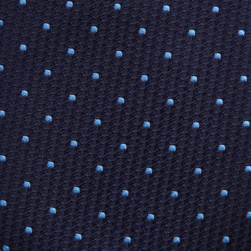 The LACE ON TONE SPOT NAVY FORD TIE by Turnbull & Asser is a rolled-up navy tie with textured fabric and an evenly spaced pattern of small light blue polka dots.