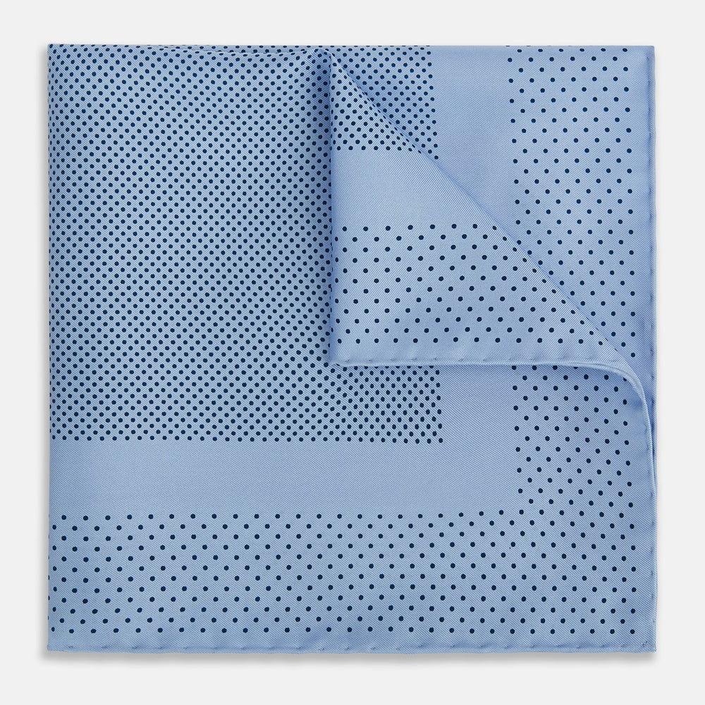 The Turnbull & Asser Pale Blue Dot Silk Pocket Square features pure silk in pale blue with a border and scattered small navy polka dots, neatly folded with one corner turned down.