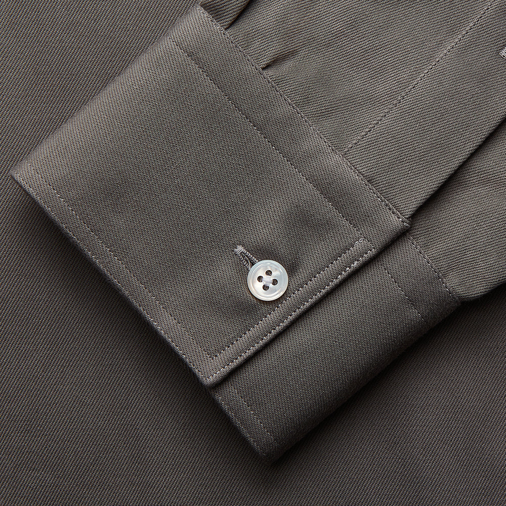The Turnbull & Asser Dusty Sage Cotton Drill Weekend Fit Nevis Shirt features a button-down collar, long sleeves, two chest pockets, and white buttons, shown folded on a white background.