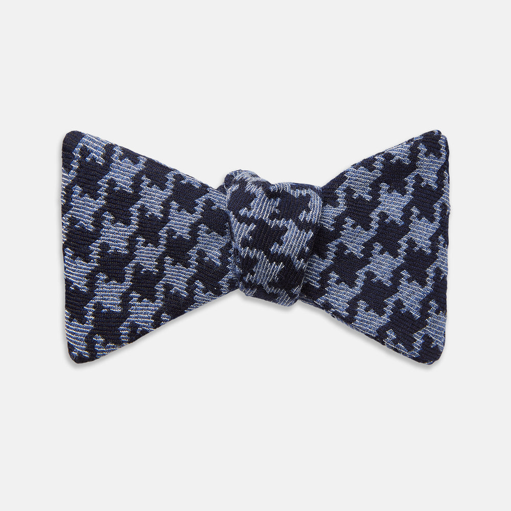 The Turnbull & Asser Navy and Blue Houndstooth Wool Blend Bow Tie features a self-tying design with a blue and black houndstooth pattern, showcased on a plain white background.