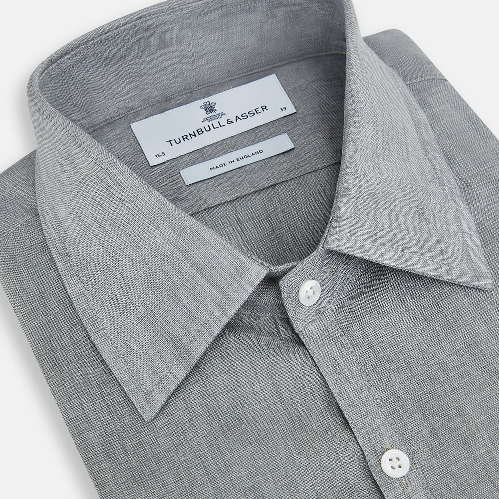 The Grey Linen Westminster Shirt by Turnbull & Asser is a long-sleeve, light gray button-up with a formal collar and white buttons, highlighting British craftsmanship and laid flat on a white background.