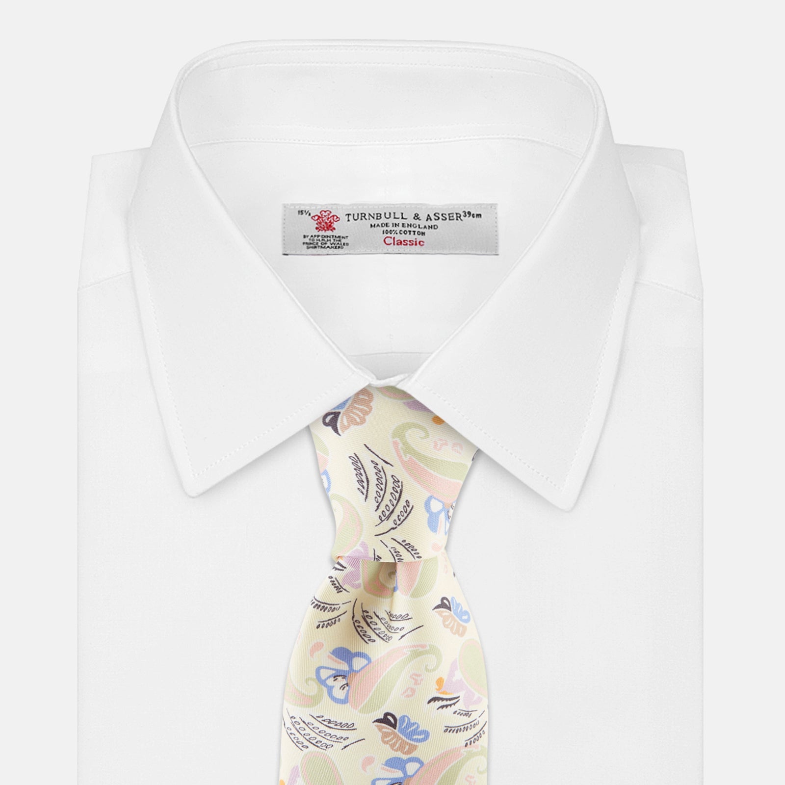 View 2 of product A rolled-up Cream Multi Bloomsbury-Inspired Pattern Silk Tie by Turnbull & Asser, featuring a pastel floral and paisley design in green, blue, pink, and orange tones, displayed on a white background.