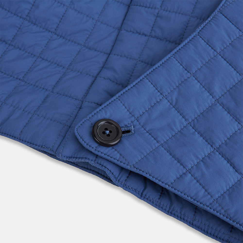 The Turnbull & Asser Azzurro Quilted Hood with Neck Warmer features a grid-stitched pattern, button closure, and overlapping front for added style. It draws inspiration from classic quilted jackets and is shown on a plain white background.