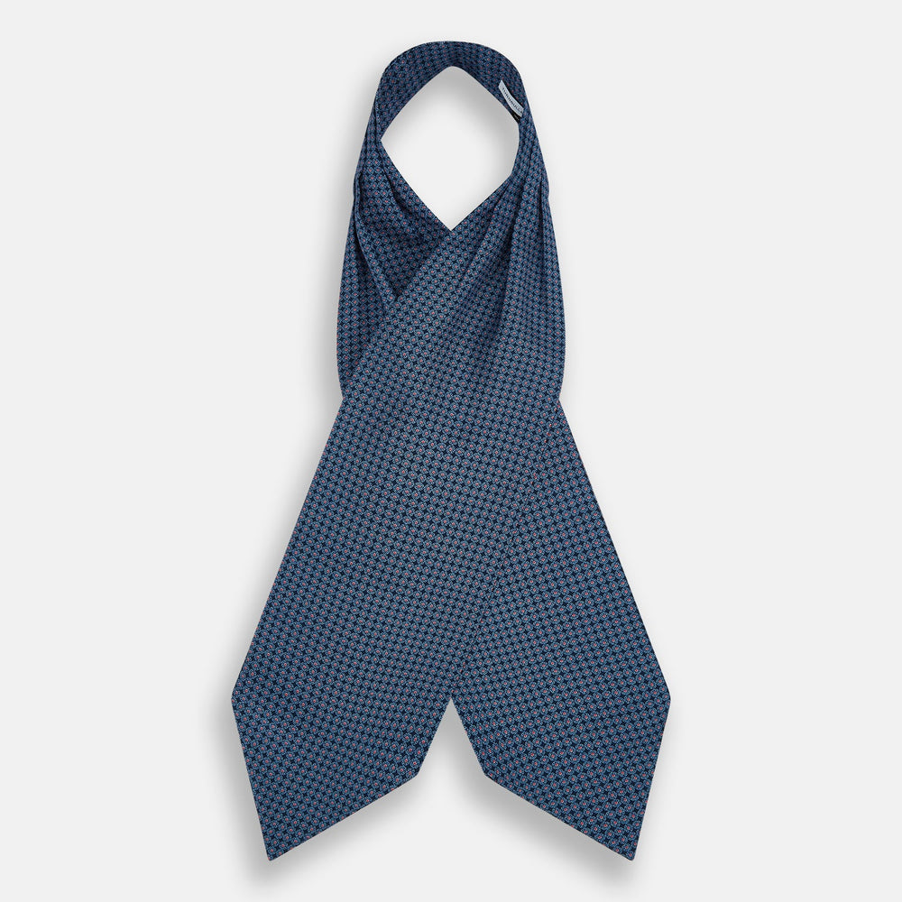 The Turnbull & Asser Navy and Red Rosette Cravat is adorned with a repeating geometric pattern of red, white, and light blue circles—an ideal formal accessory displayed against a white background.