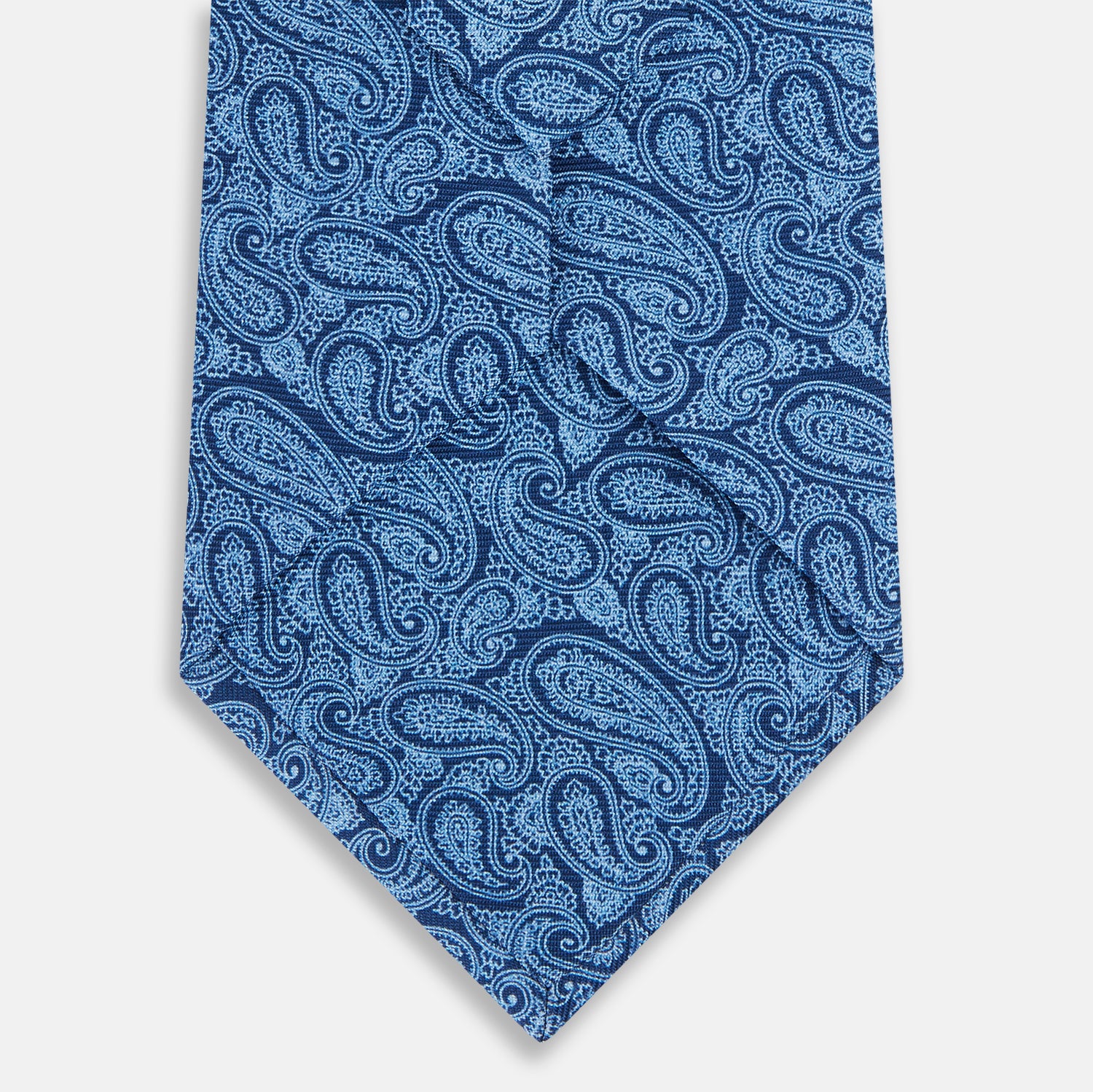 View 3 of product The Turnbull & Asser Azzurro Paisley Silk Tie showcases an intricate light blue paisley pattern on rich blue silk, presented rolled up on a white background.
