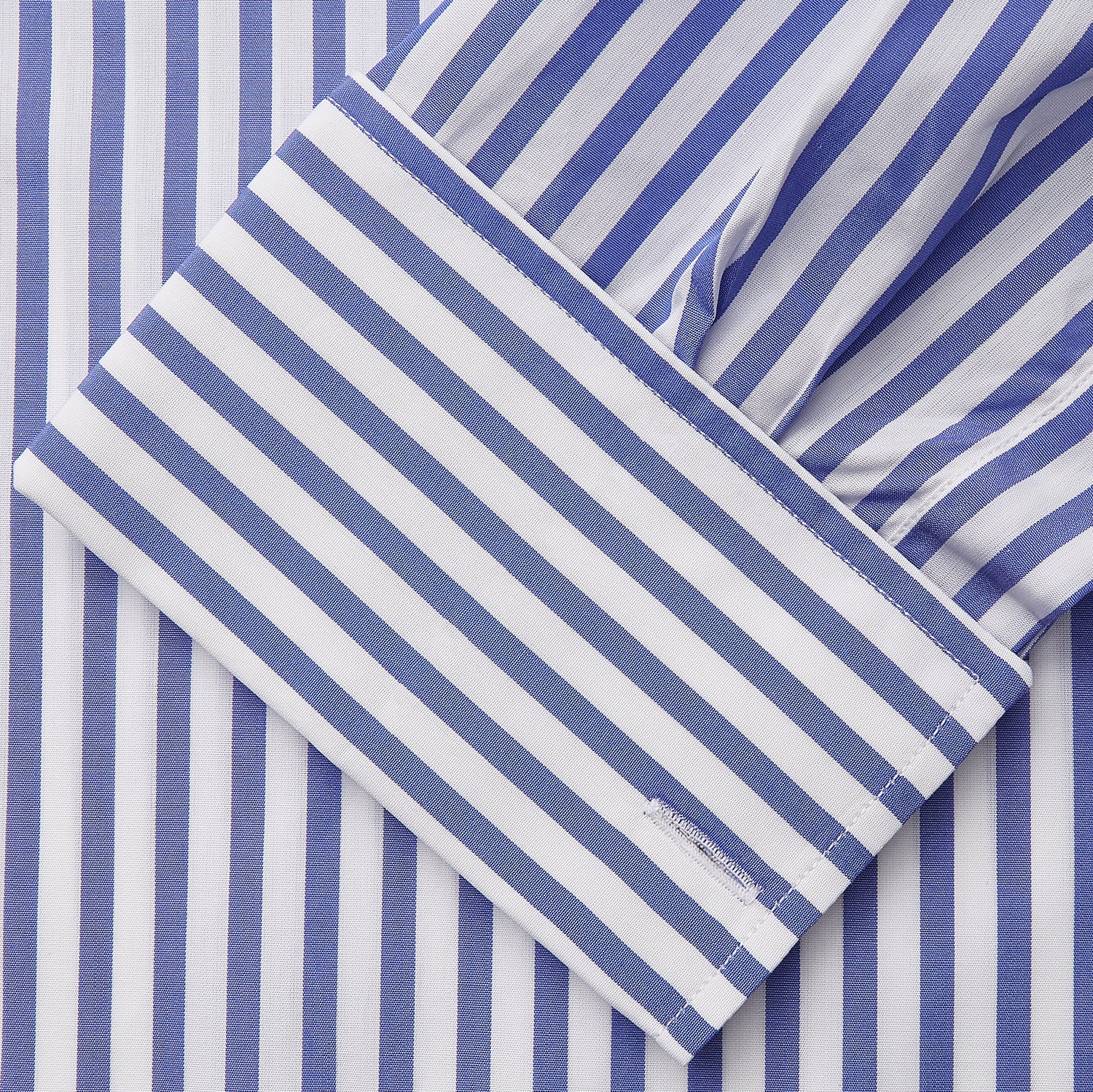 View 4 of product The Turnbull & Asser Pale Blue Candy Stripe Cotton Marlene Shirt is an oversized women's collared shirt with long sleeves, buttoned cuffs, and vertical blue and white stripes, shown laid flat on a white background.