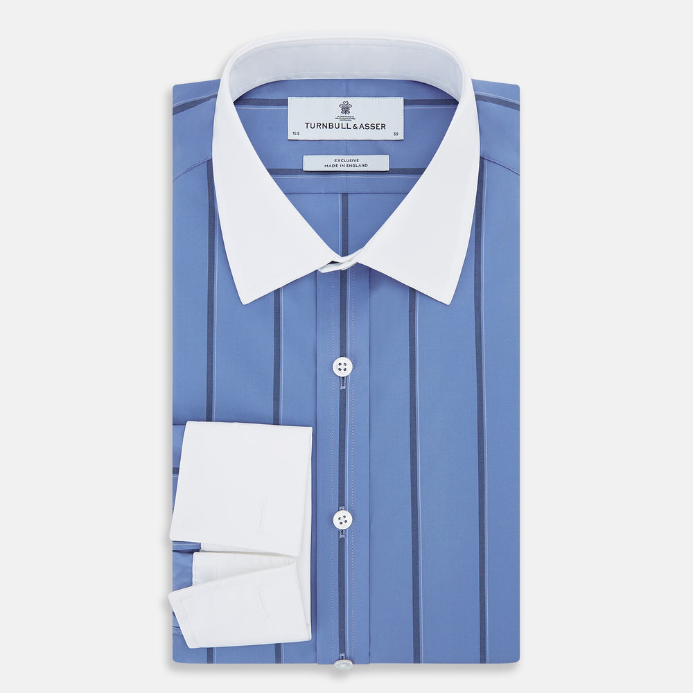 The Turnbull & Asser Colony Blue Track Stripe Shirt features vertical dark blue stripes, a Mayfair fit, and contrast white T&A collar and cuffs, reflecting British craftsmanship against a plain light background.