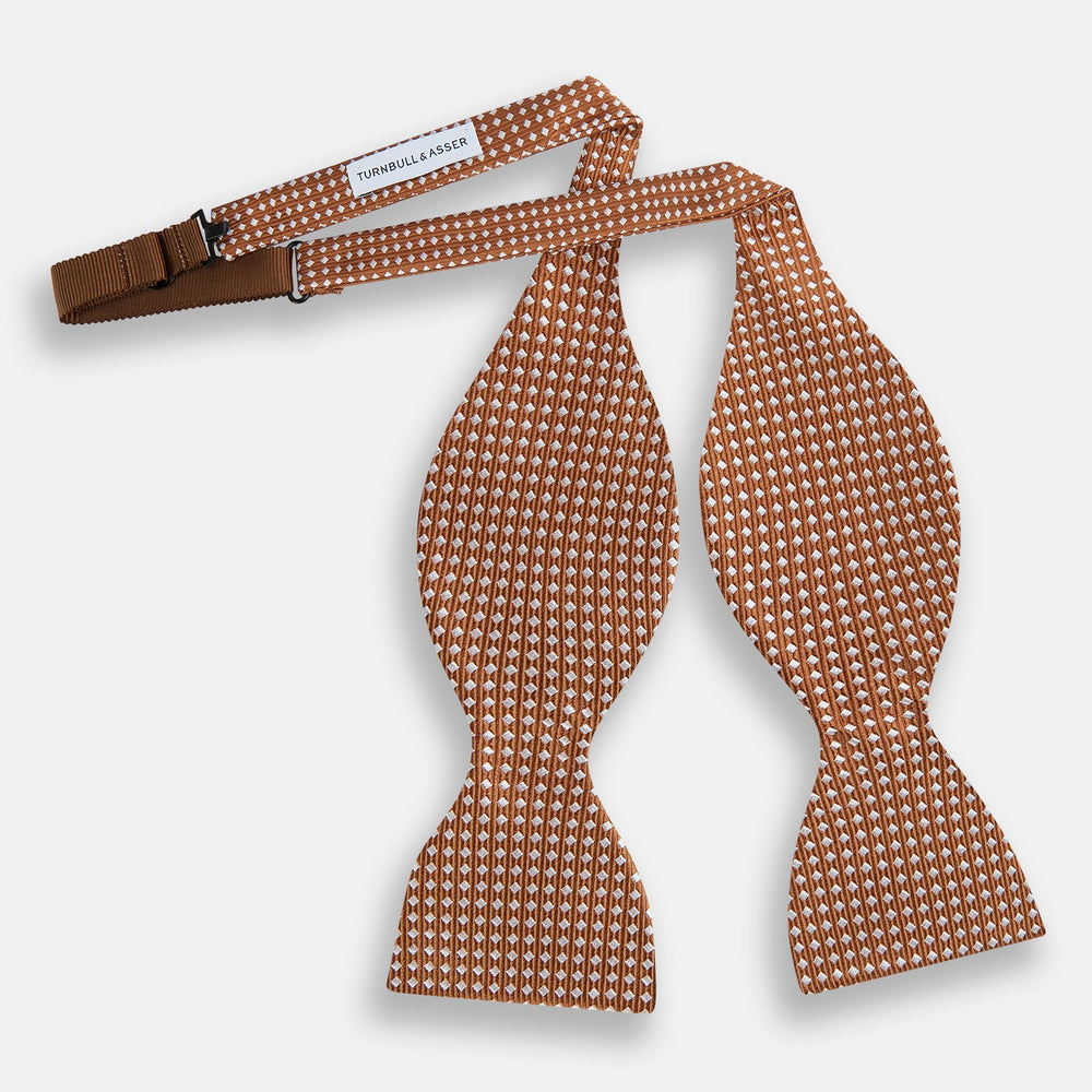 The Turnbull & Asser Brown and White Diamond Silk Bow Tie features a diamond pattern, ideal for formal occasions, showcased on a white background.