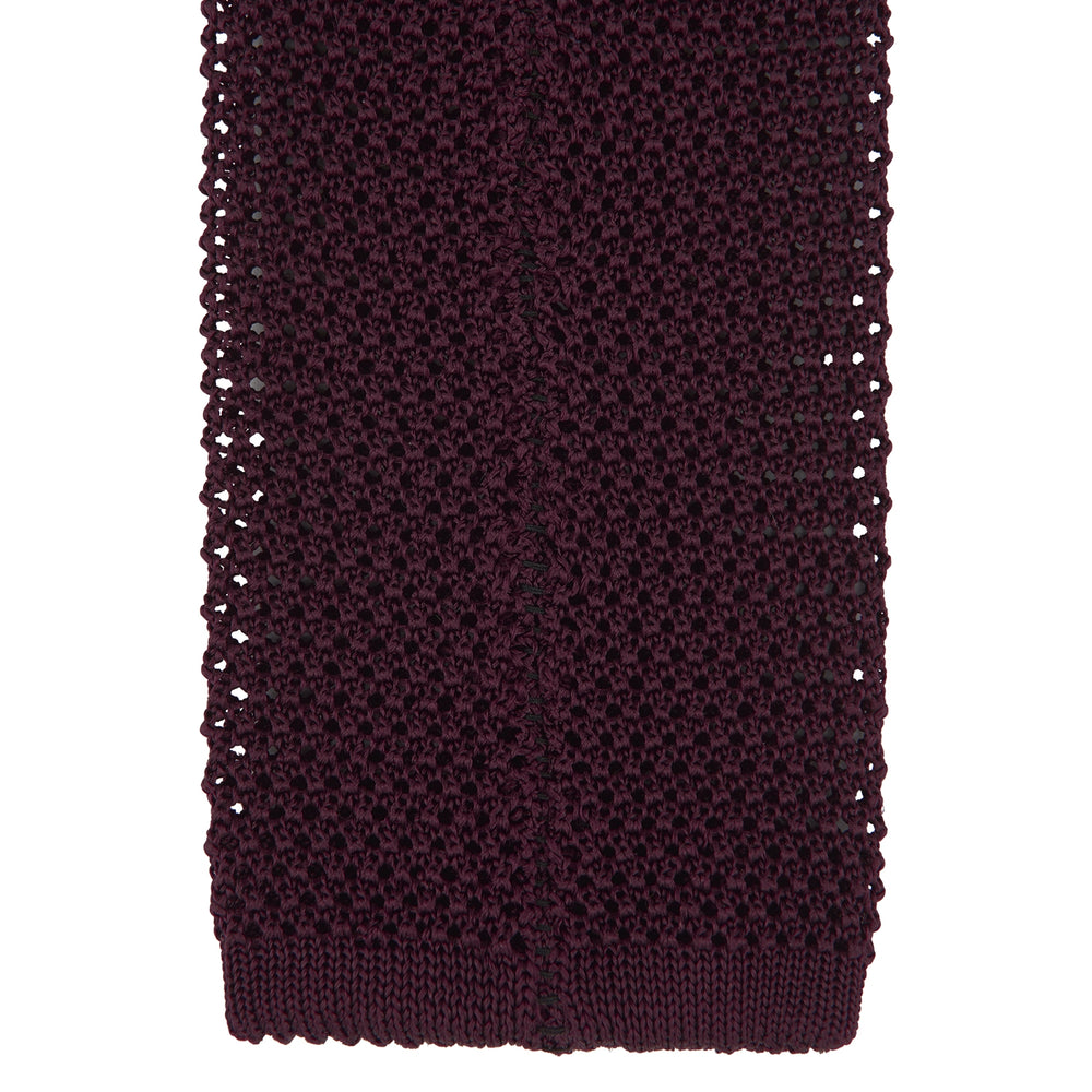 The Turnbull & Asser MTIE011-ZAI003 TIES 7.5CM is a plain burgundy tie shown rolled on a white background, featuring straight edges and textured knit—ideal for the modern gentleman’s versatile wardrobe.