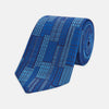 View 1 of product The Turnbull & Asser Blue Motif Printed Foulard Silk Tie showcases a geometric pattern in varying blue shades, making it a striking and essential accessory for any wardrobe.