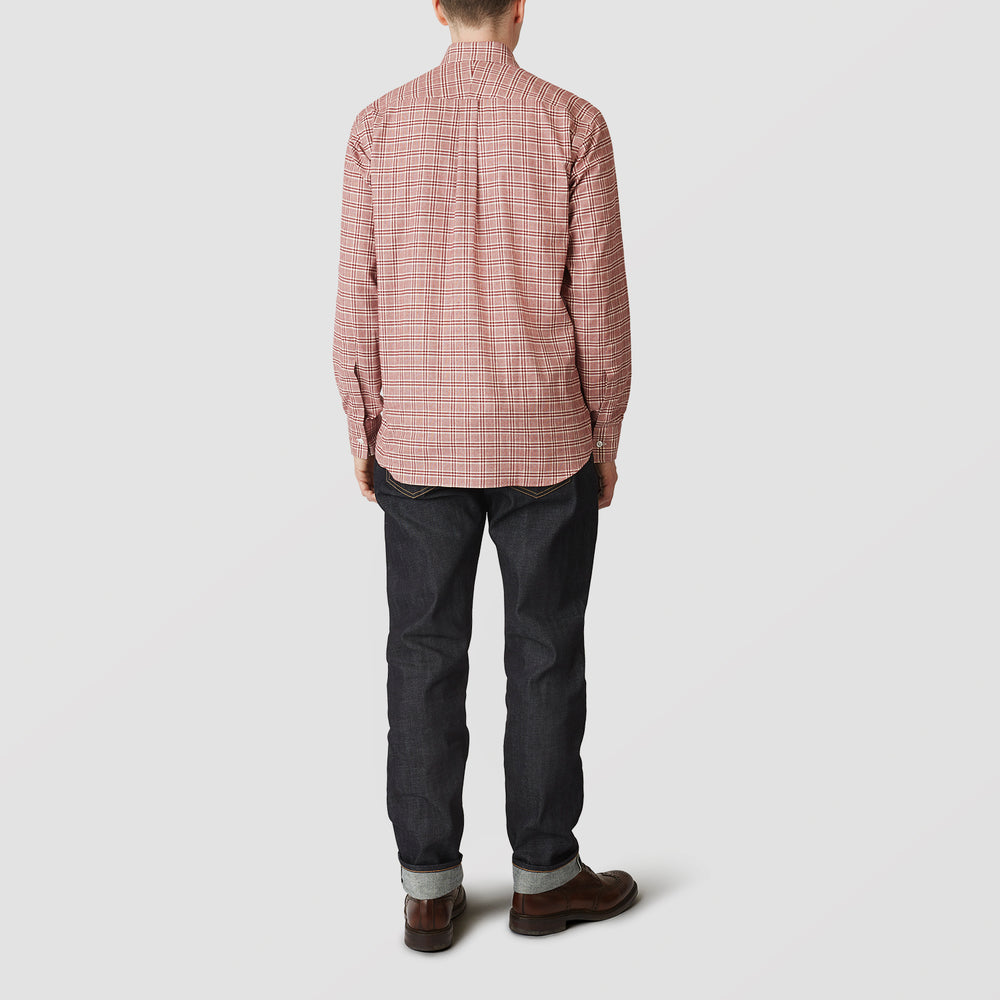 A person in a Turnbull & Asser Red Check Weekend Fit Shirt with a Derby collar and 1-button cuffs, paired with dark cuffed jeans and brown shoes, stands against a plain light background for an ideal winter layered style.